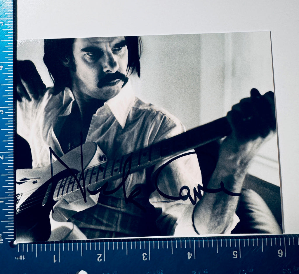 • Nick Cave autographed 4x6 black and white photograph featuring an authentic hand-signed signature, framed against a professional blue grading calibration ruler.
