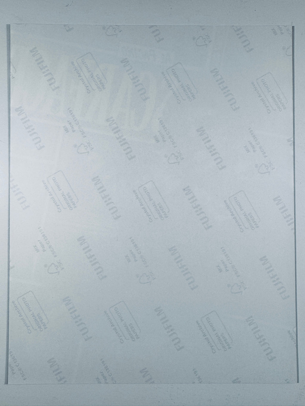 The plain white reverse side of a photographic print showing translucent Fujifilm crystal archive paper watermarks and logos.
