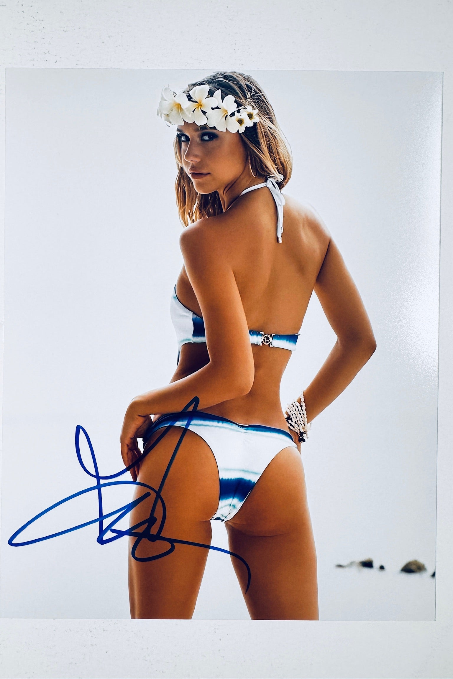 Signed full photo of Alexis Ren posing in a white and blue tie-dye bikini with a floral crown, featuring a blue autograph.
