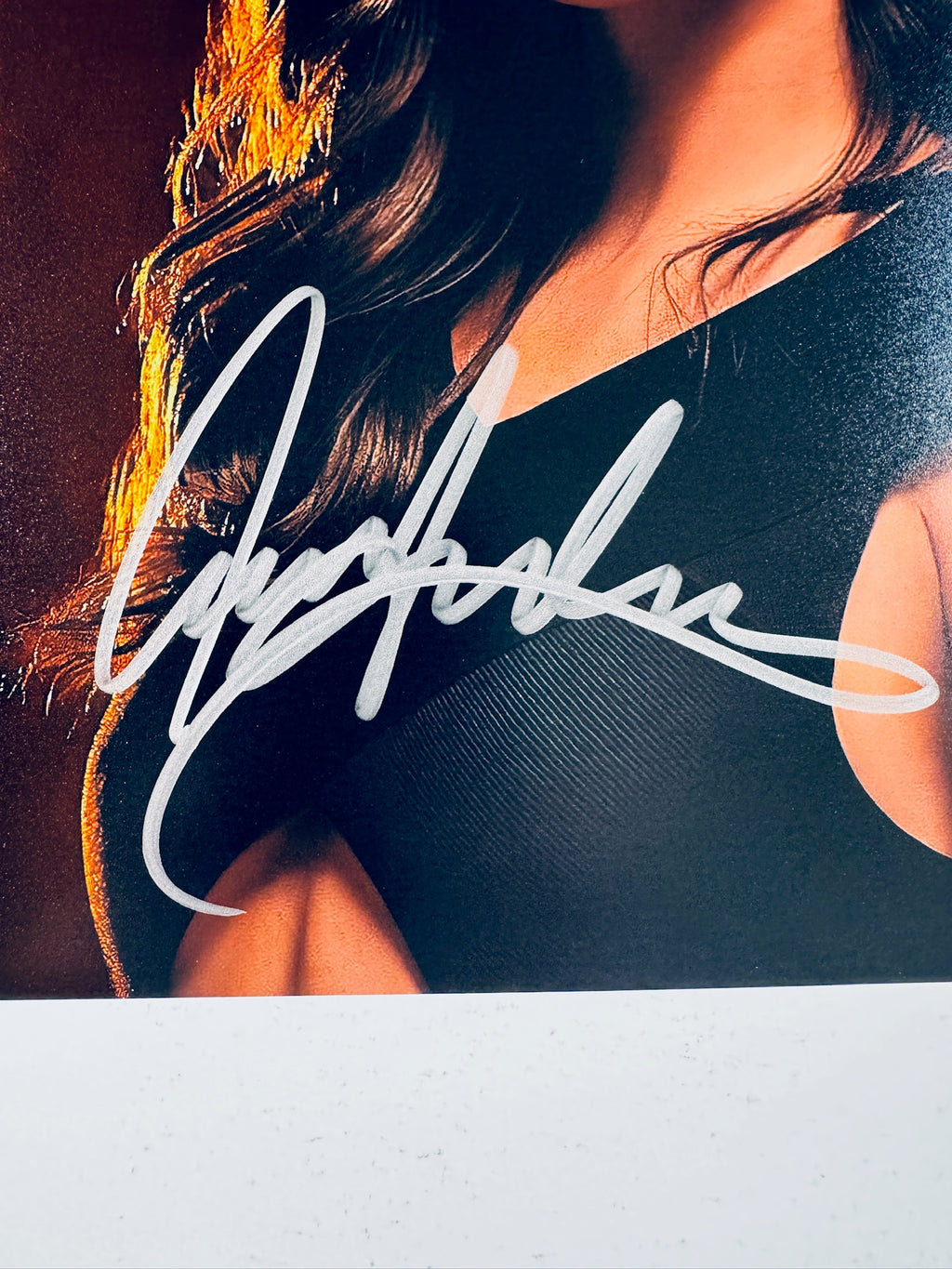 Close-up view of Ana de Armas's silver autograph across her chest and shoulder on the promotional photograph.
