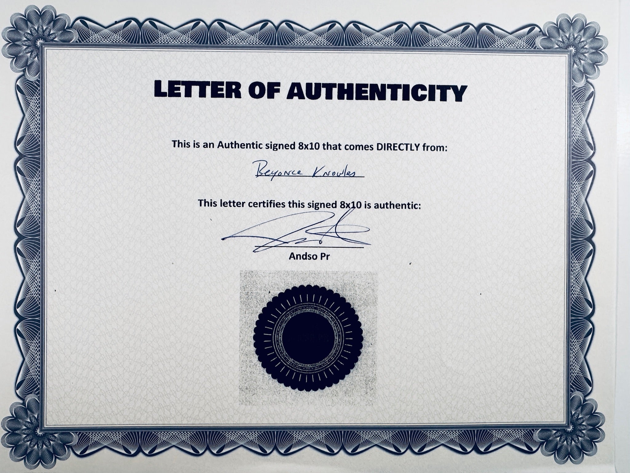 A Letter of Authenticity with a decorative blue-patterned border, certifying an authentic signed 8x10 coming directly from Beyoncé Knowles, featuring a signature and a dark circular seal graphic at the bottom.