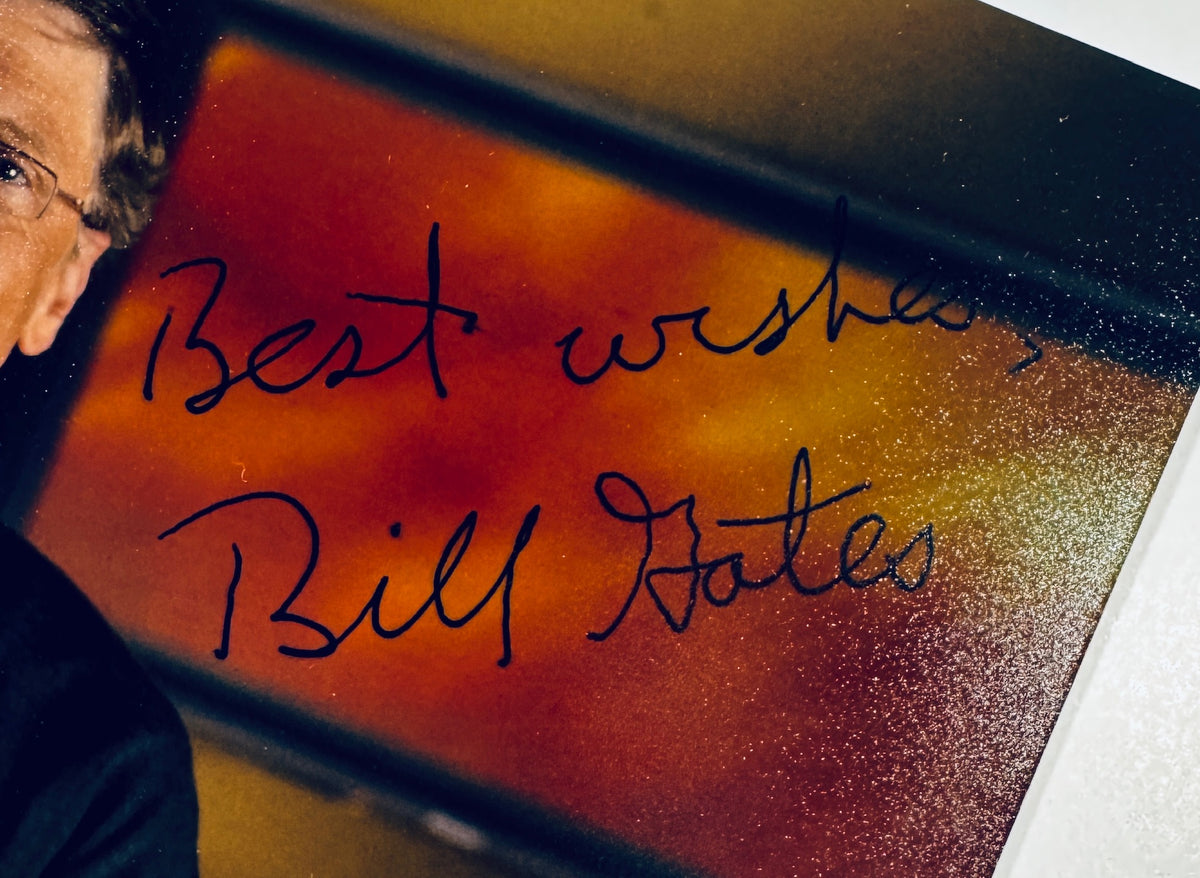 Extreme close-up detail of Bill Gates signature and inscription reading Best wishes, Bill Gates on photograph.