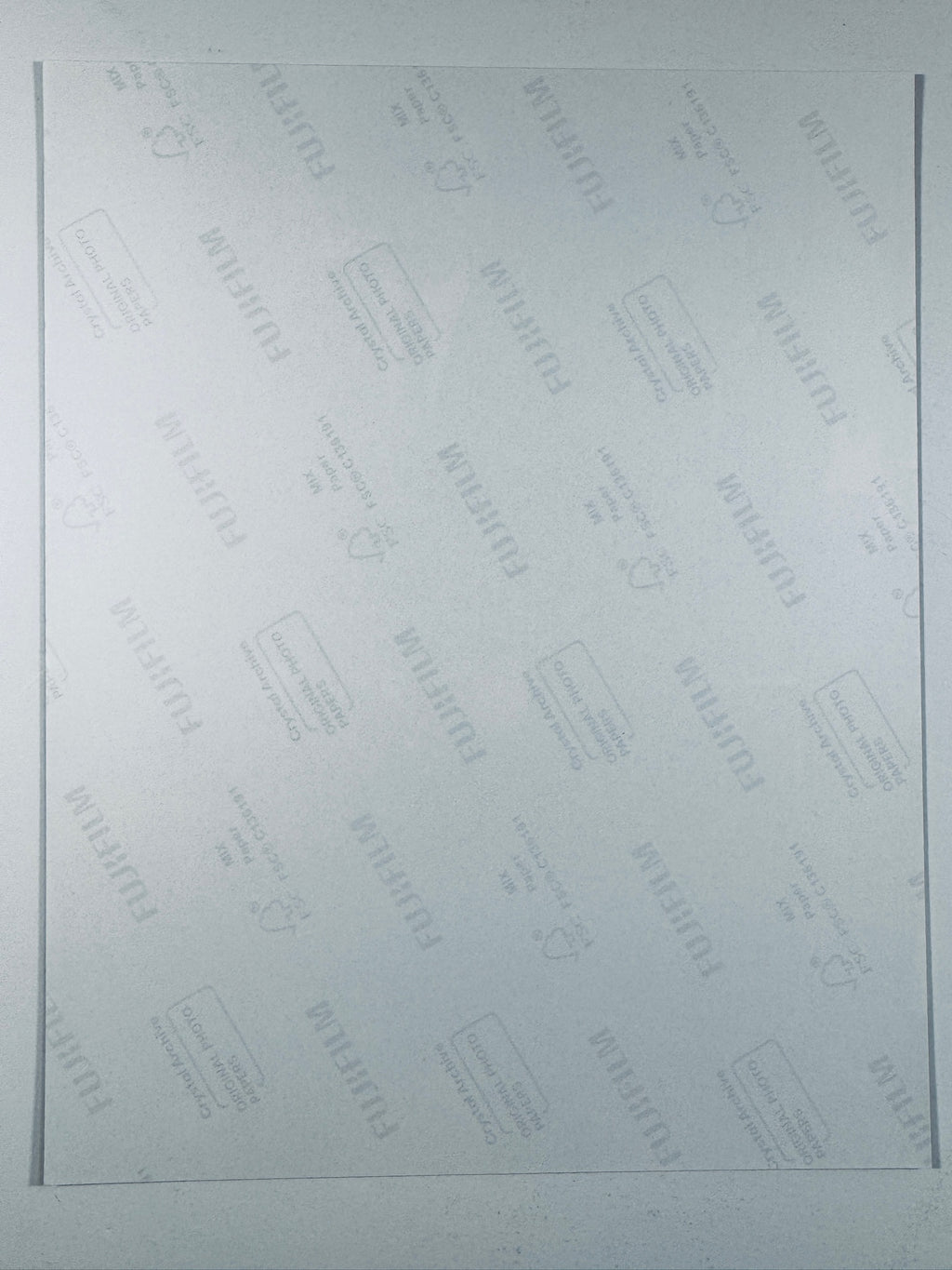 he plain white reverse side of a photographic print showing translucent Fujifilm crystal archive paper watermarks and logos.