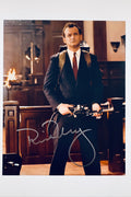 A portrait of Bill Murray as Peter Venkman wearing a dark suit and red tie, holding a proton pack wand, featuring a signature across the lower area.