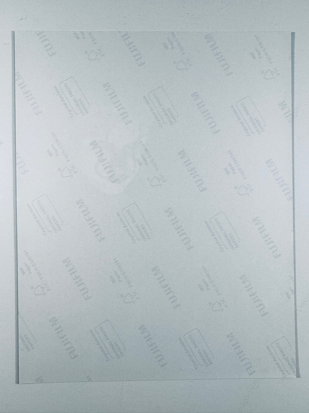 The plain white reverse side of a photographic print showing translucent Fujifilm crystal archive paper watermarks and logos.