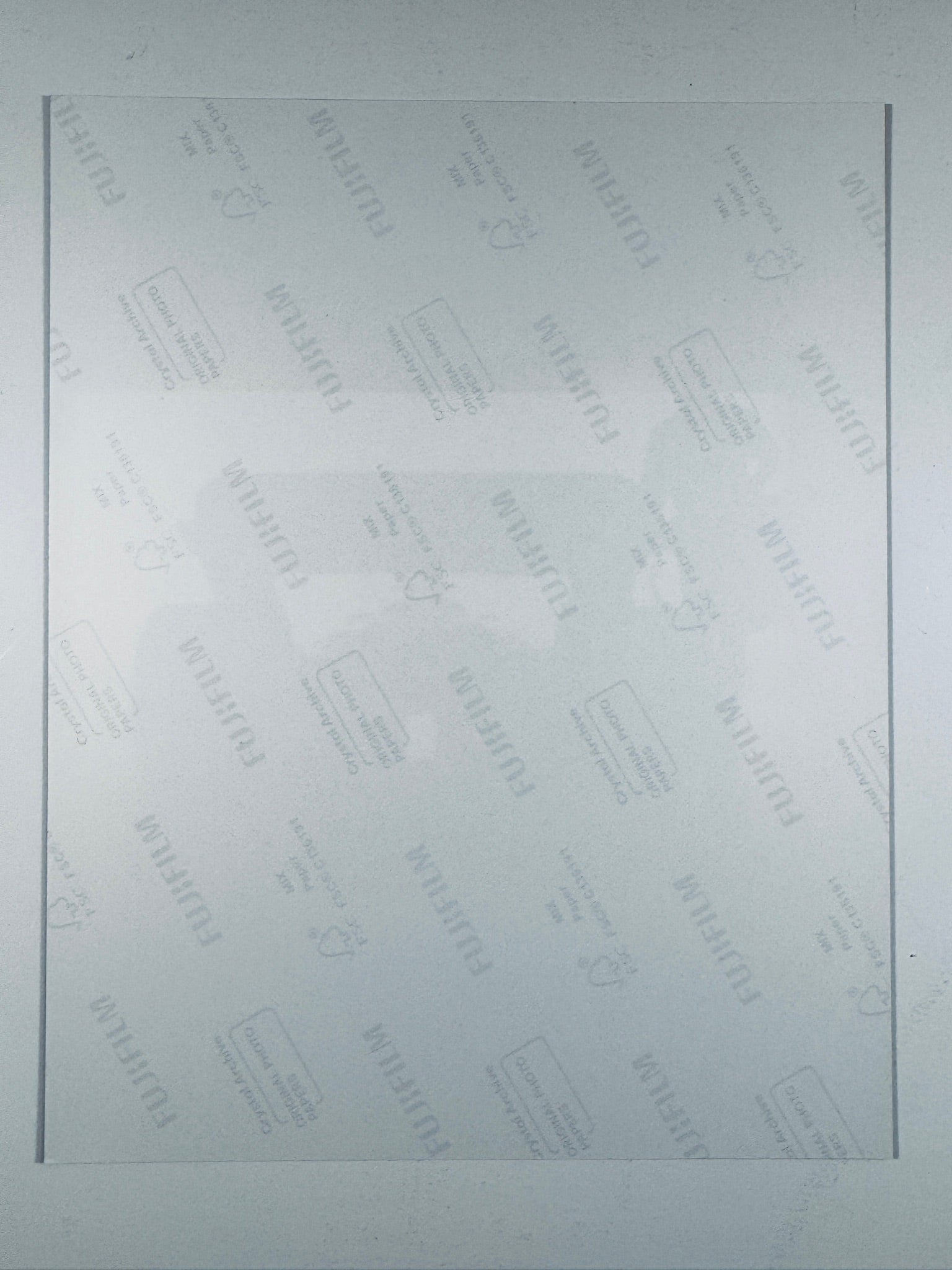 The plain white reverse side of a photographic print showing translucent Fujifilm crystal archive paper watermarks and logos.