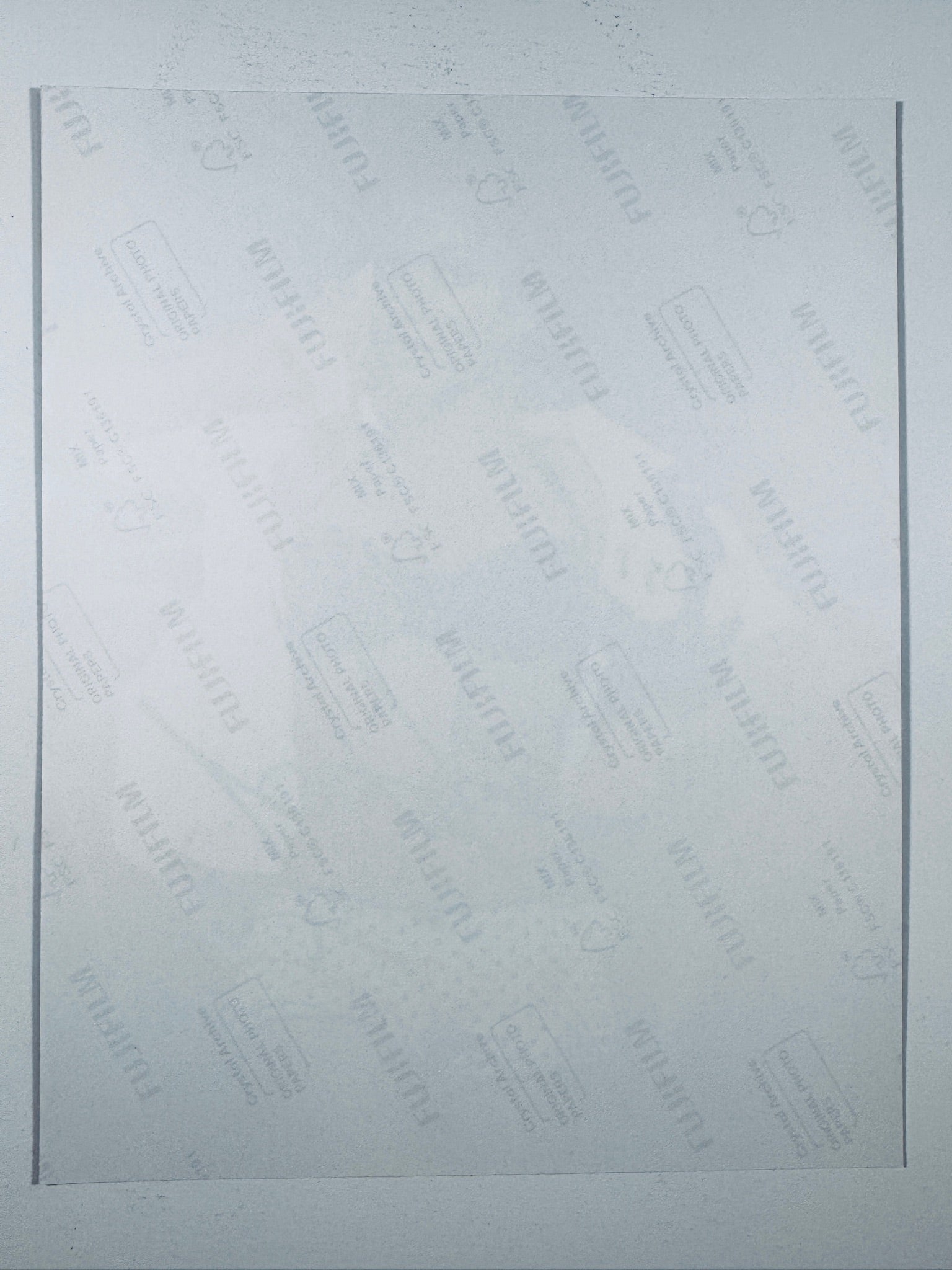 The plain white reverse side of a photographic print showing translucent Fujifilm crystal archive paper watermarks and logos.
