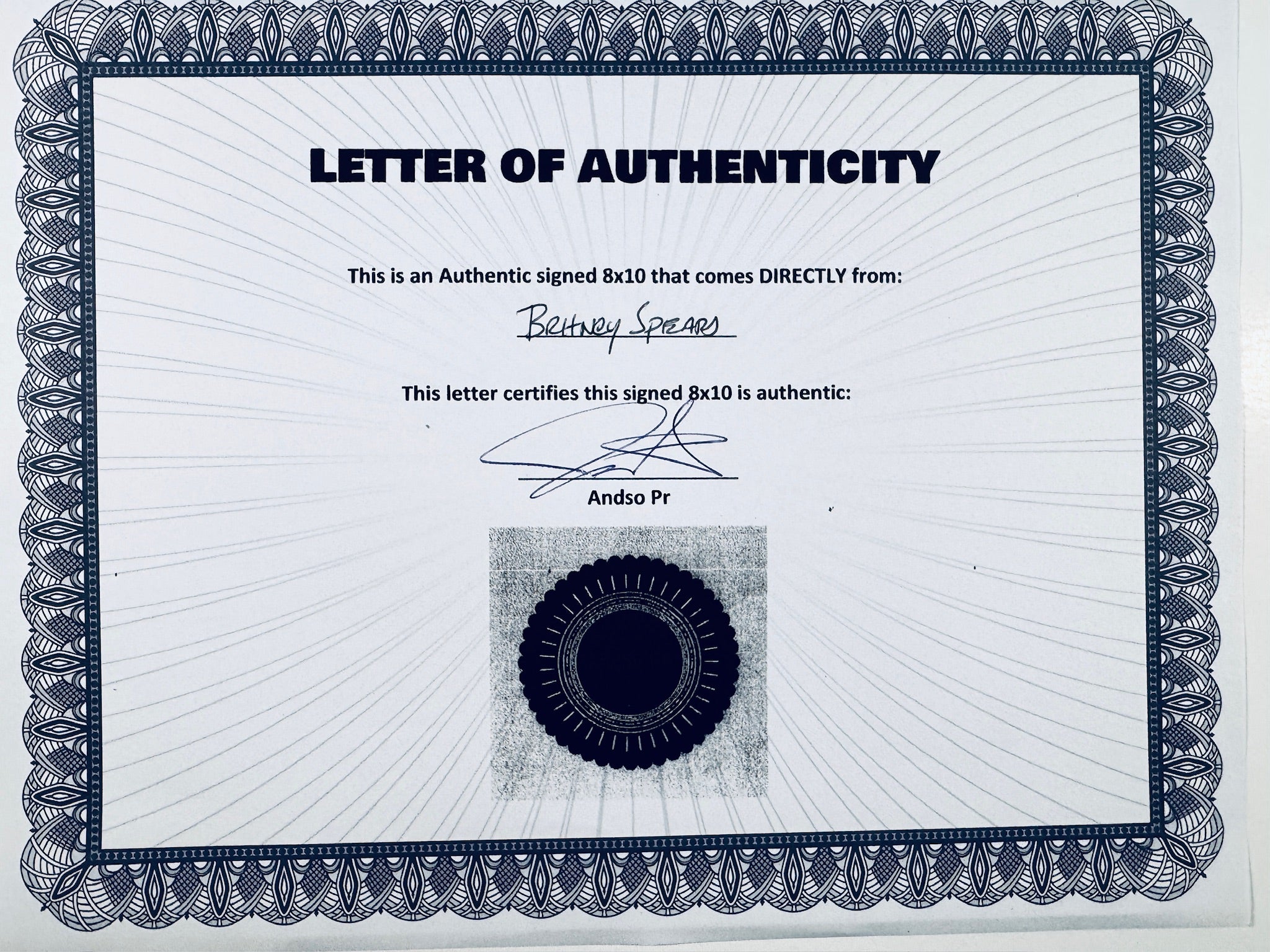 A Letter of Authenticity with a decorative blue-patterned border, certifying an authentic signed 8x10 coming directly from Britney Spears, featuring a dark circular seal graphic at the bottom.