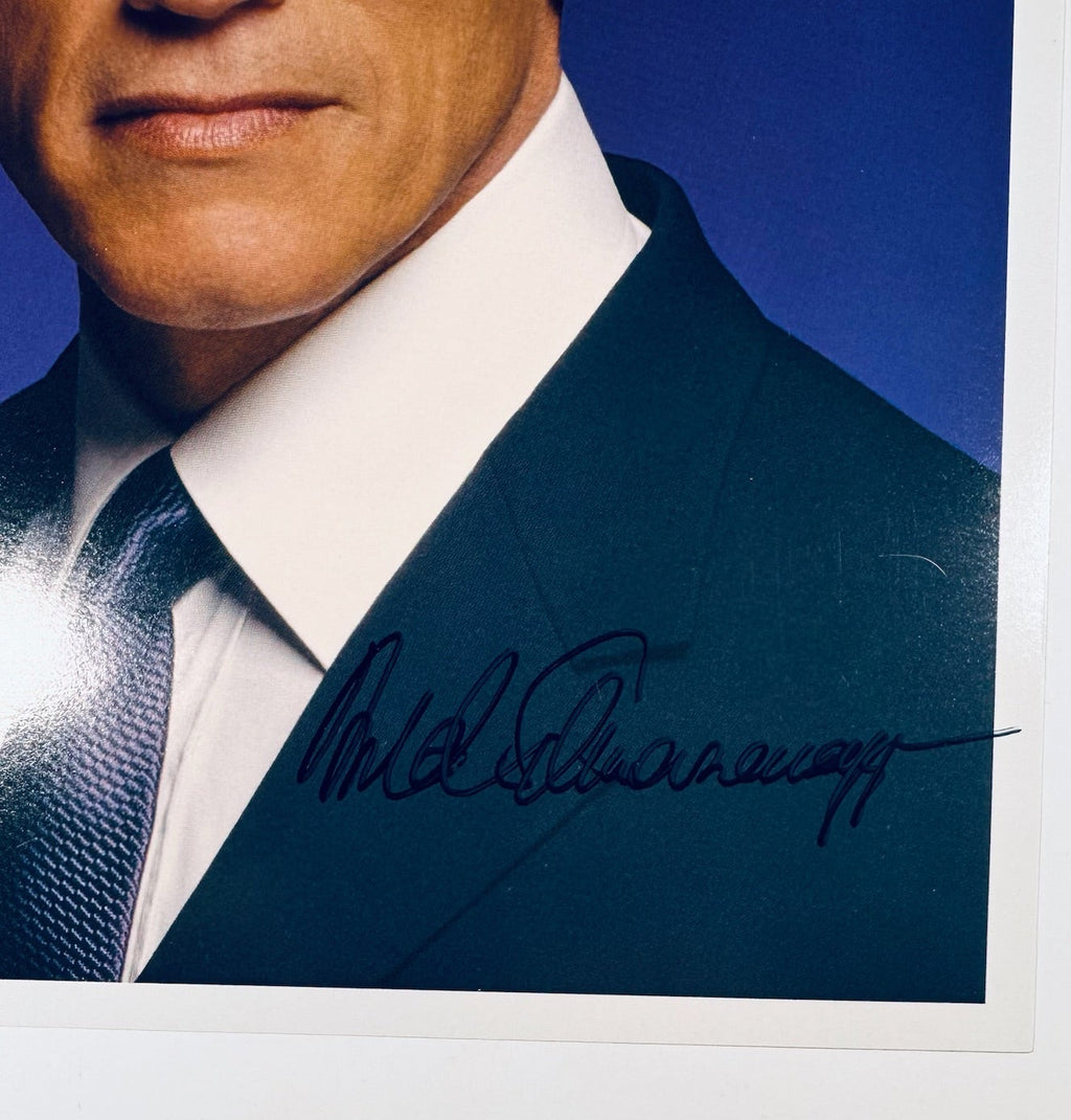 Detailed close-up of Arnold Schwarzenegger autograph signature on suit jacket of color photo.