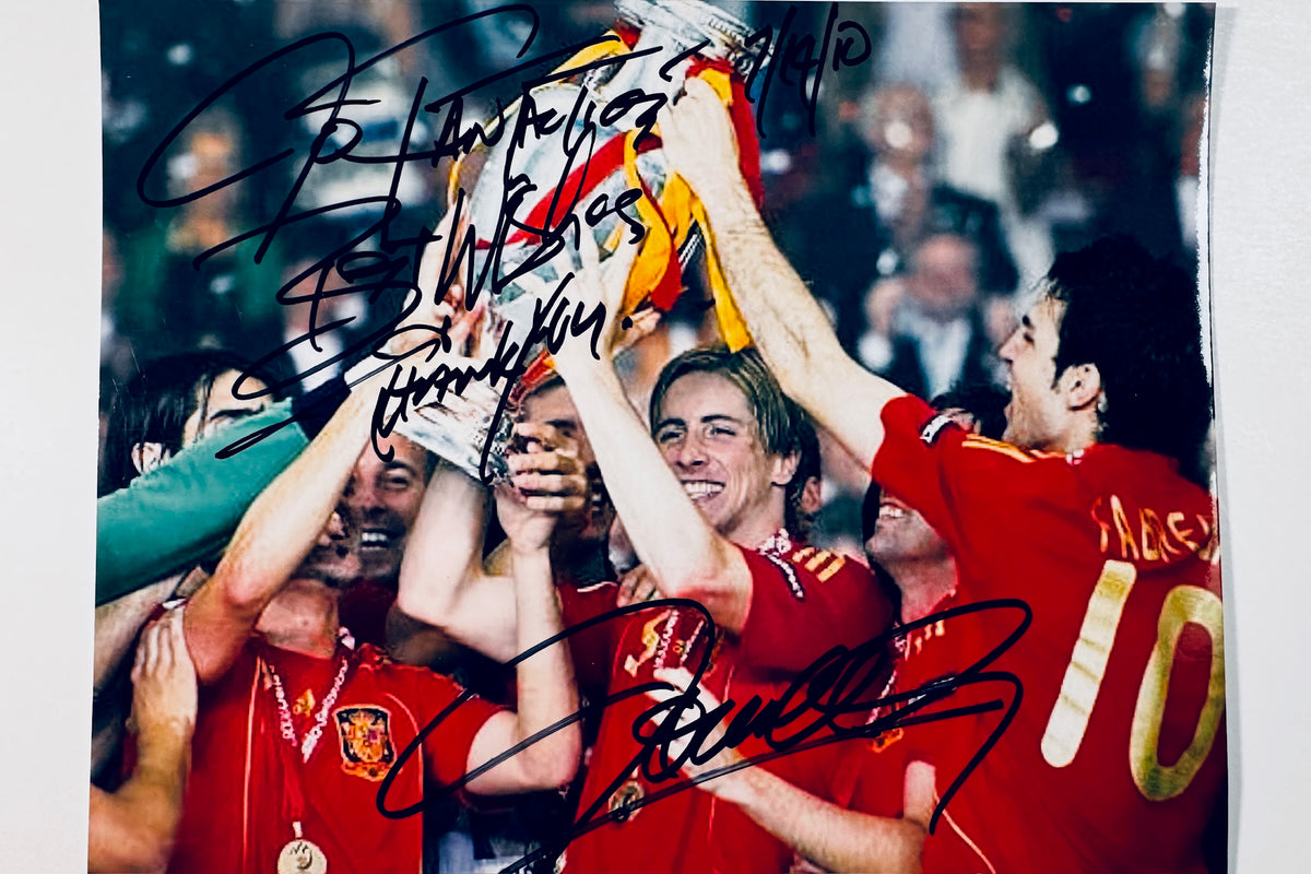 Autographed color photograph of Carles Puyol and Spain national team lifting the trophy hand-signed in black marker.