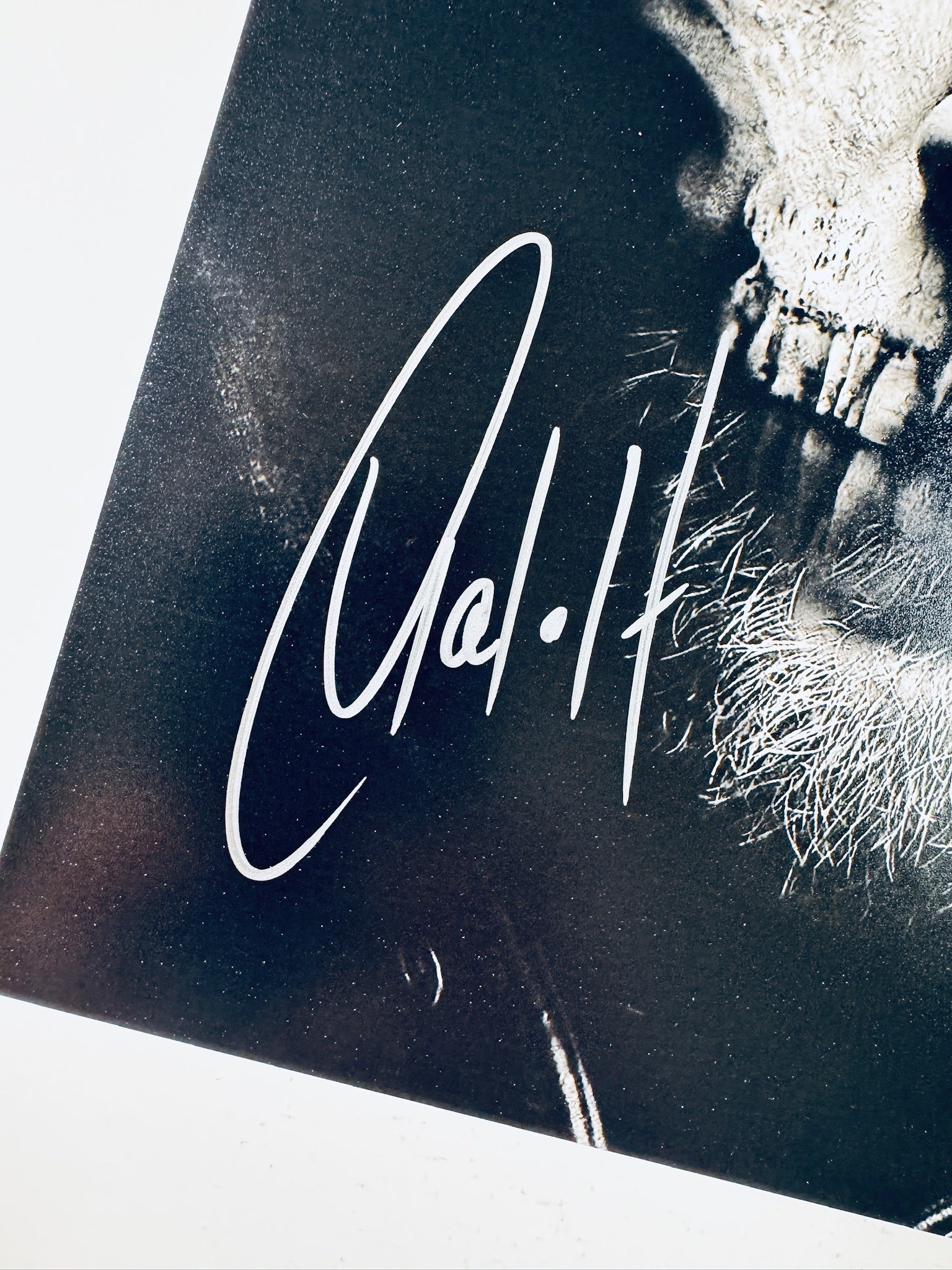 Close-up view of Charlie Hunnam's silver signature next to the skull face makeup portion of the Sons of Anarchy promotional photograph.
