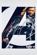 A promotional poster portrait of Chris Hemsworth as Thor from The Avengers, featuring the character's arm holding Mjolnir and a partial view of his face and armor, with a silver autograph signed across the center.