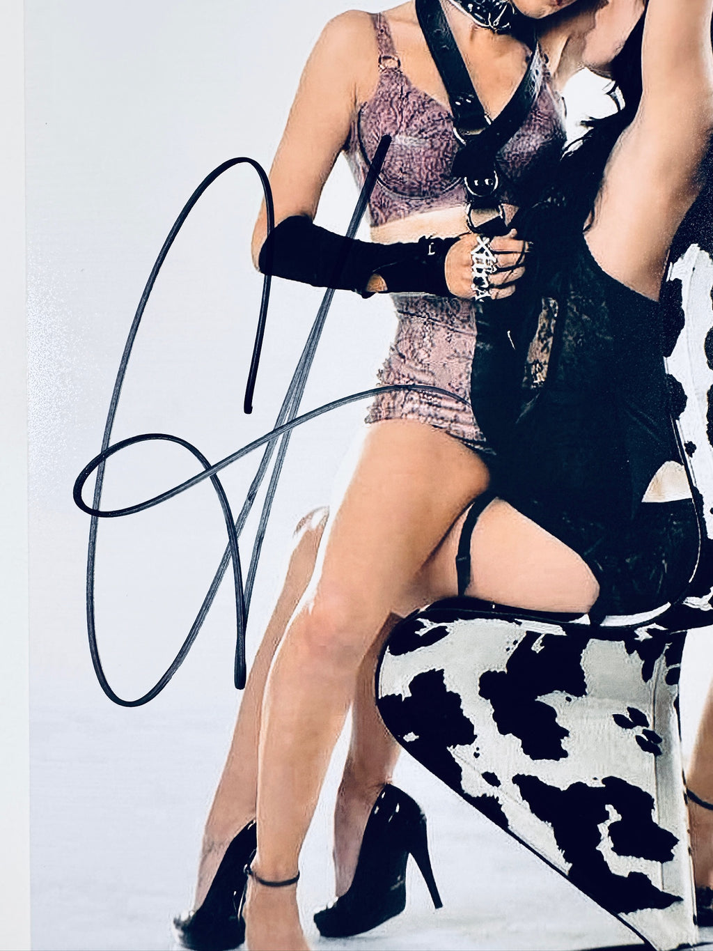 Close-up view of Christina Aguilera's black signature across her leg and the chair on the promotional photograph.