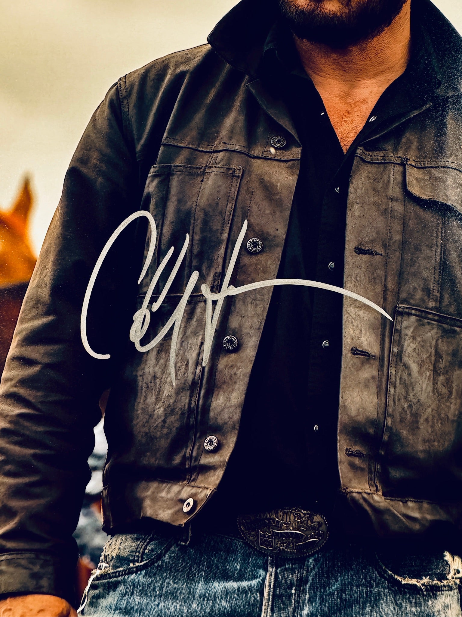 Close-up view of Cole Hauser's silver signature across the jacket of the Yellowstone promotional photograph.