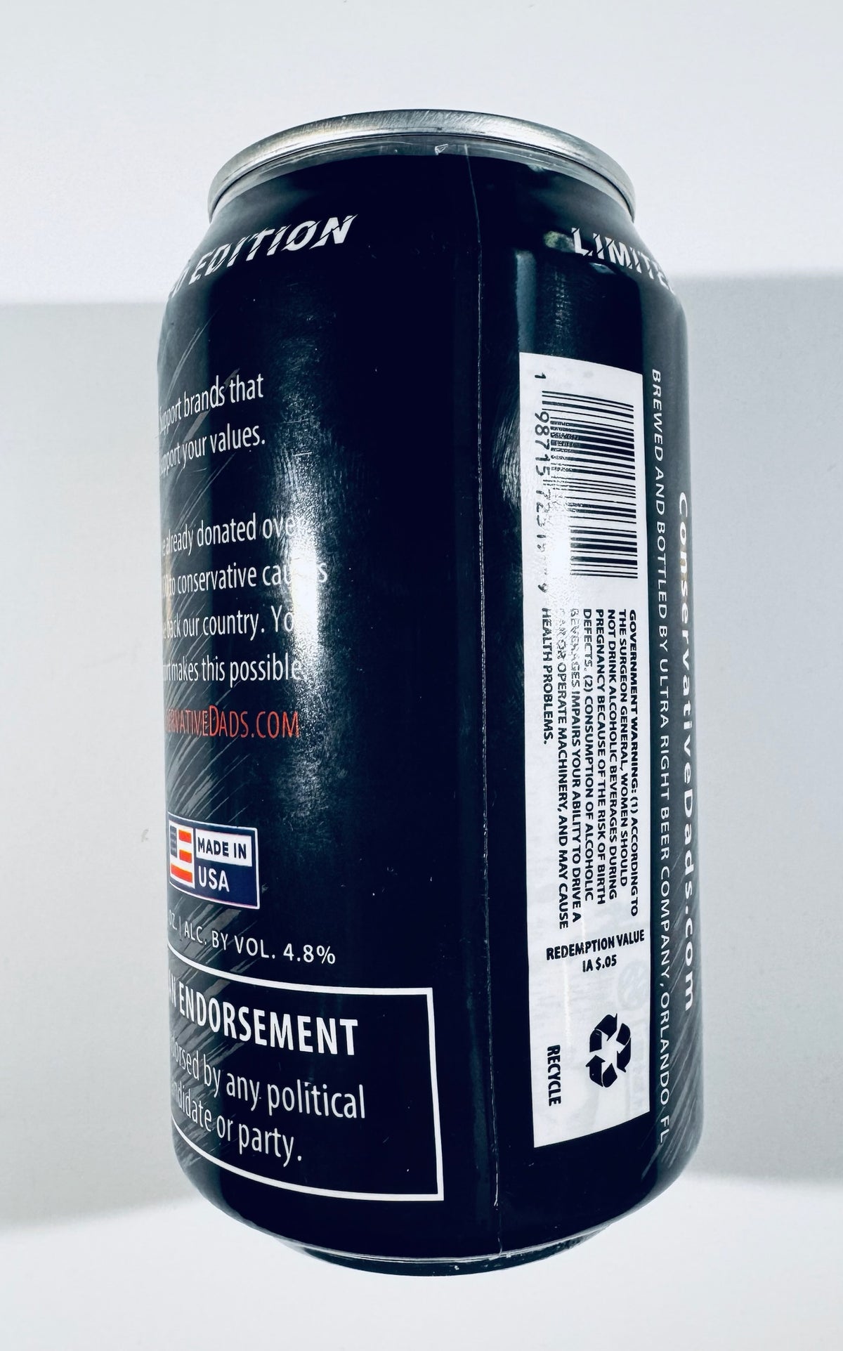 A black aluminum beverage can shown from the side against a plain light background, with white text and a barcode label visible on the can.