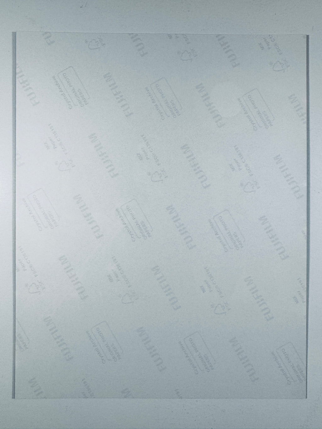 The plain white reverse side of a photographic print showing translucent Fujifilm crystal archive paper watermarks and logos.