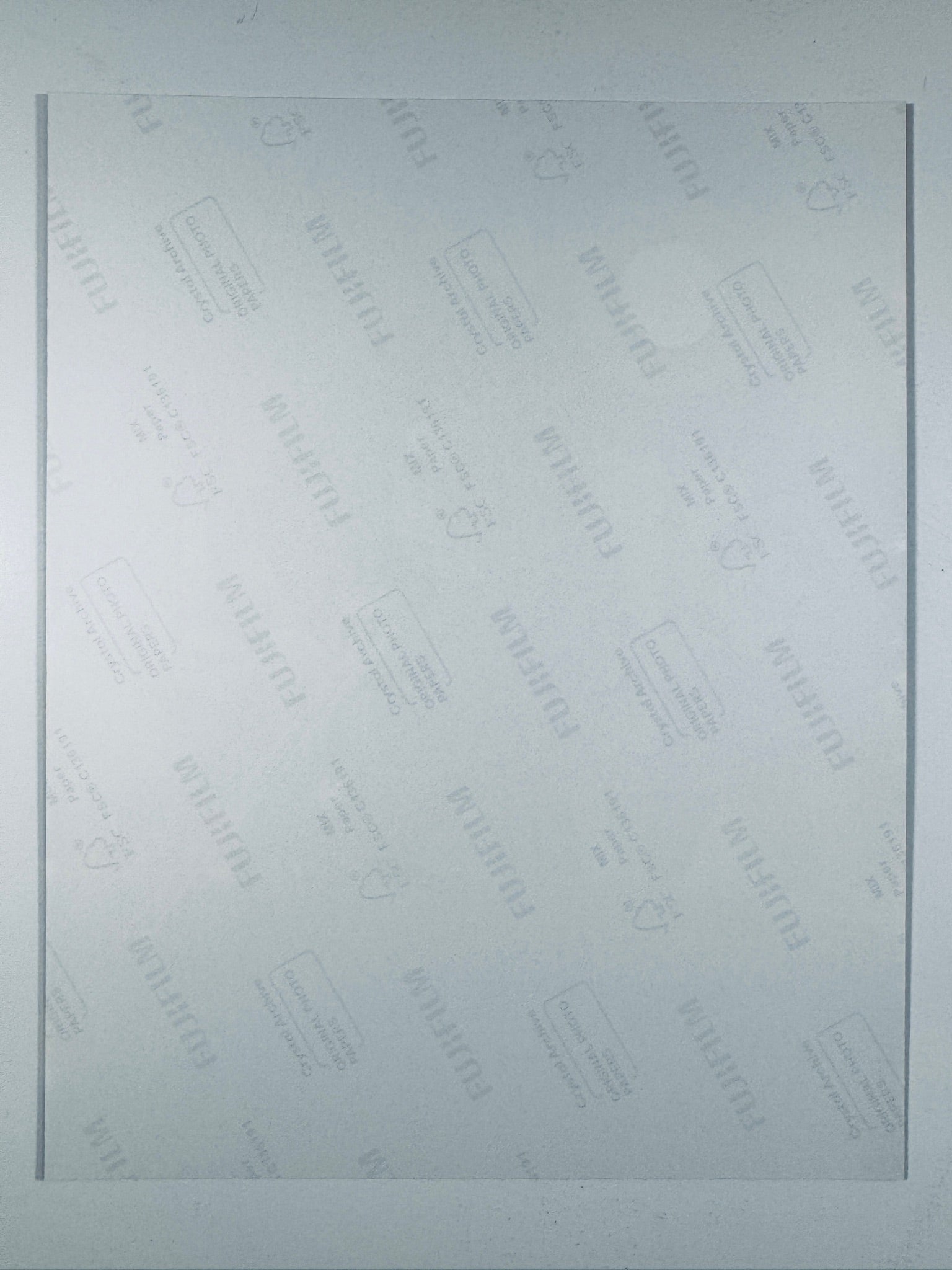 The plain white reverse side of a photographic print showing translucent Fujifilm crystal archive paper watermarks and logos.