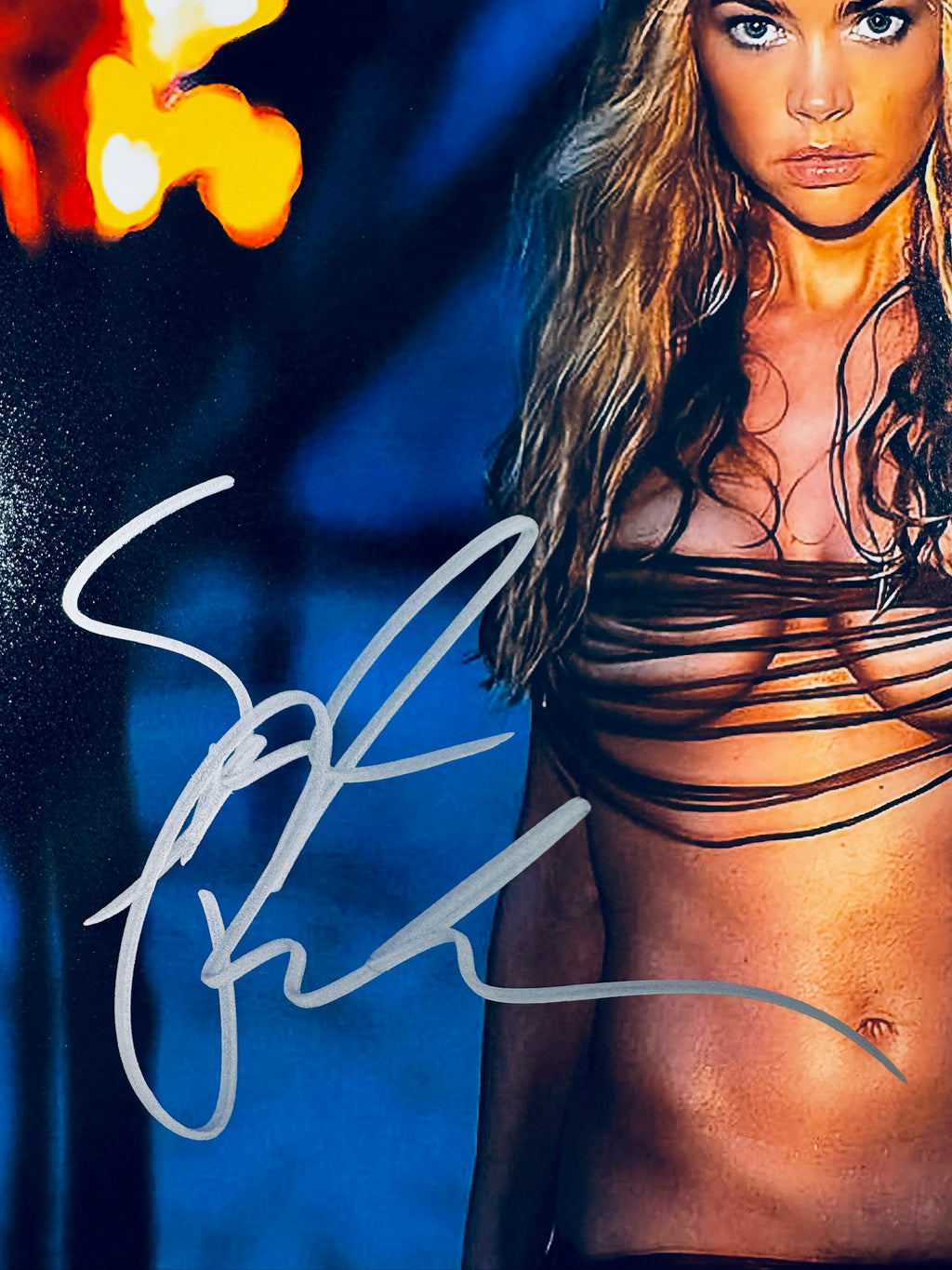 Close-up view of Denise Richards's silver autograph across the side of the promotional photograph.