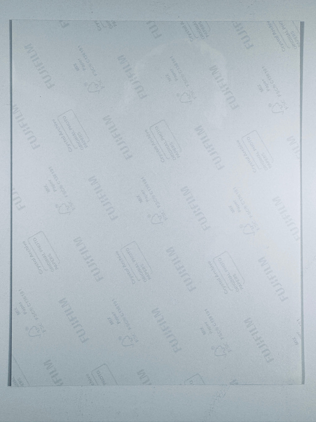 The plain white reverse side of a photographic print showing translucent Fujifilm crystal archive paper watermarks and logos.