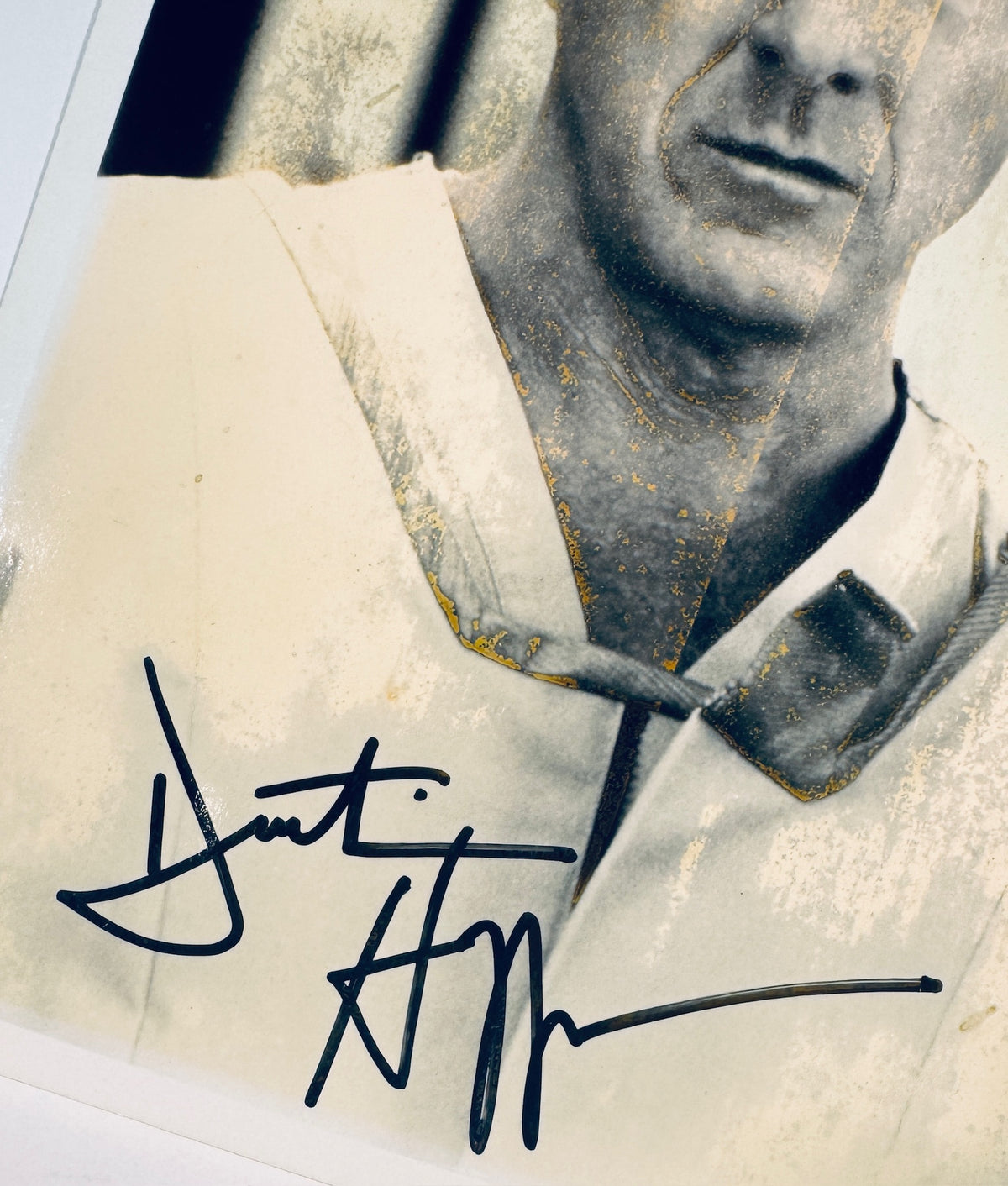 Close-up detail of Dustin Hoffman's signature in black sharpie on the bottom of a vintage photo.
