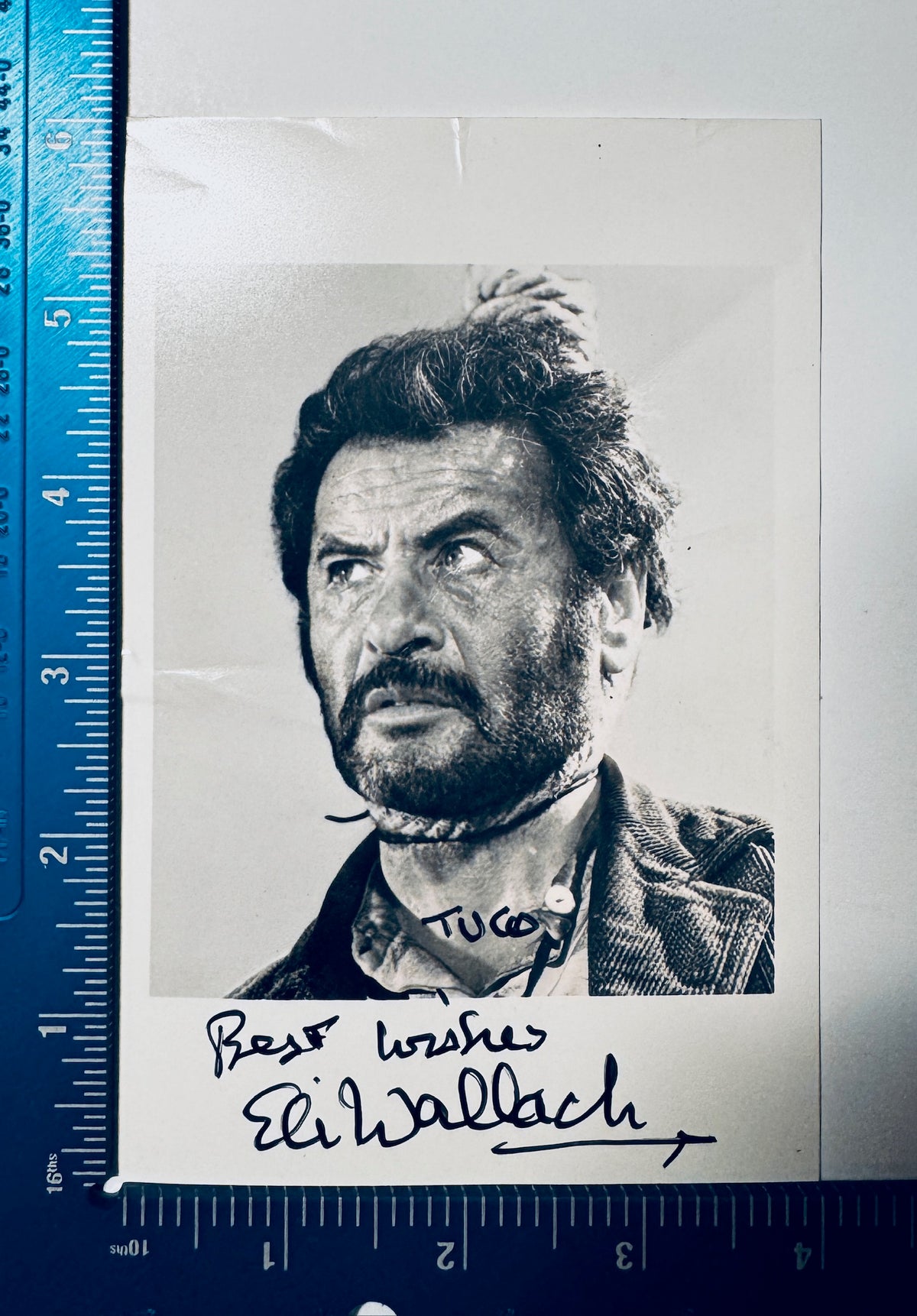 Eli Wallach autographed photo measured with precision ruler showing dimensions approx 3.5x5.5 inches.