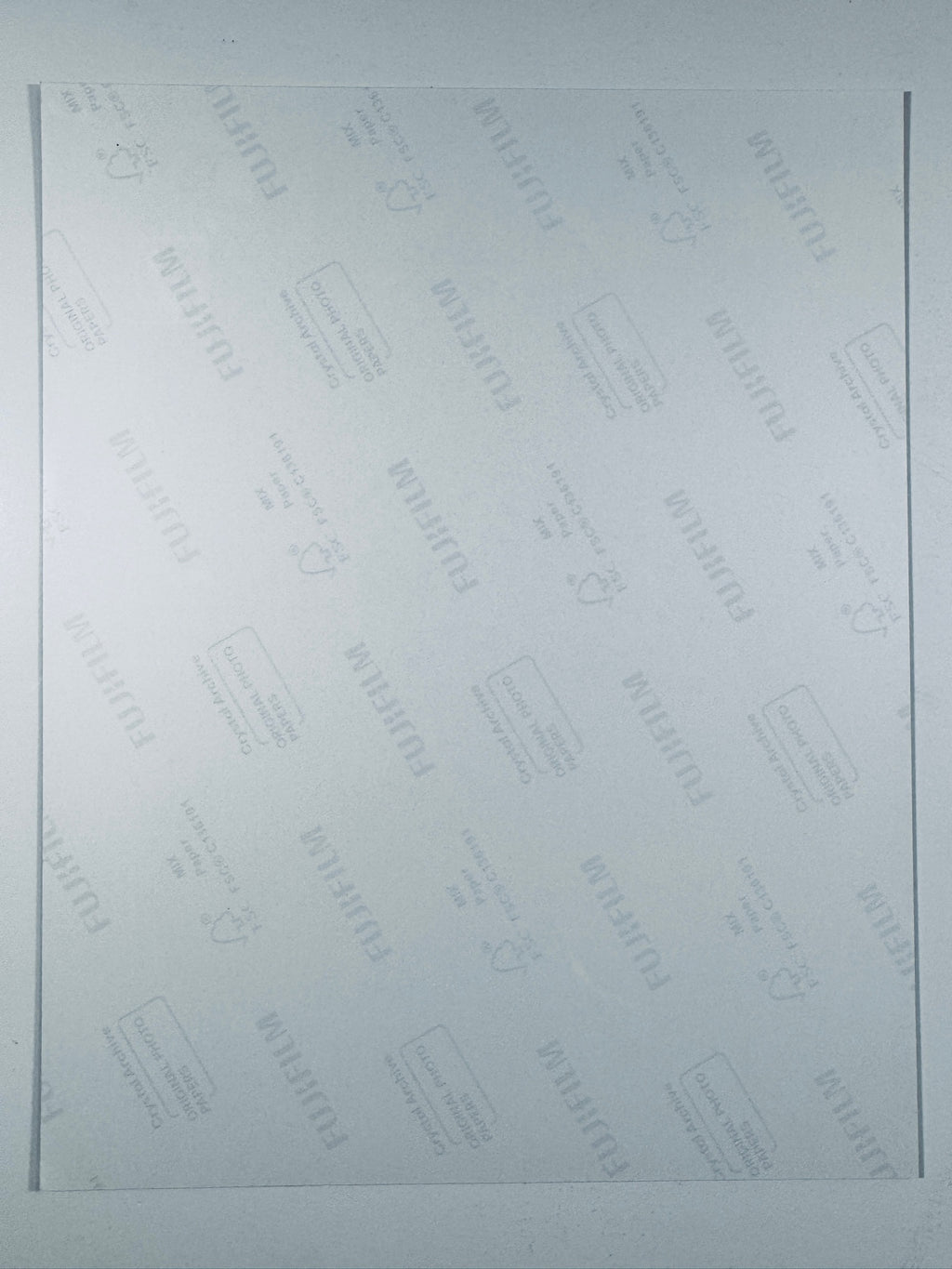 The plain white reverse side of a photographic print showing translucent Fujifilm crystal archive paper watermarks and logos.