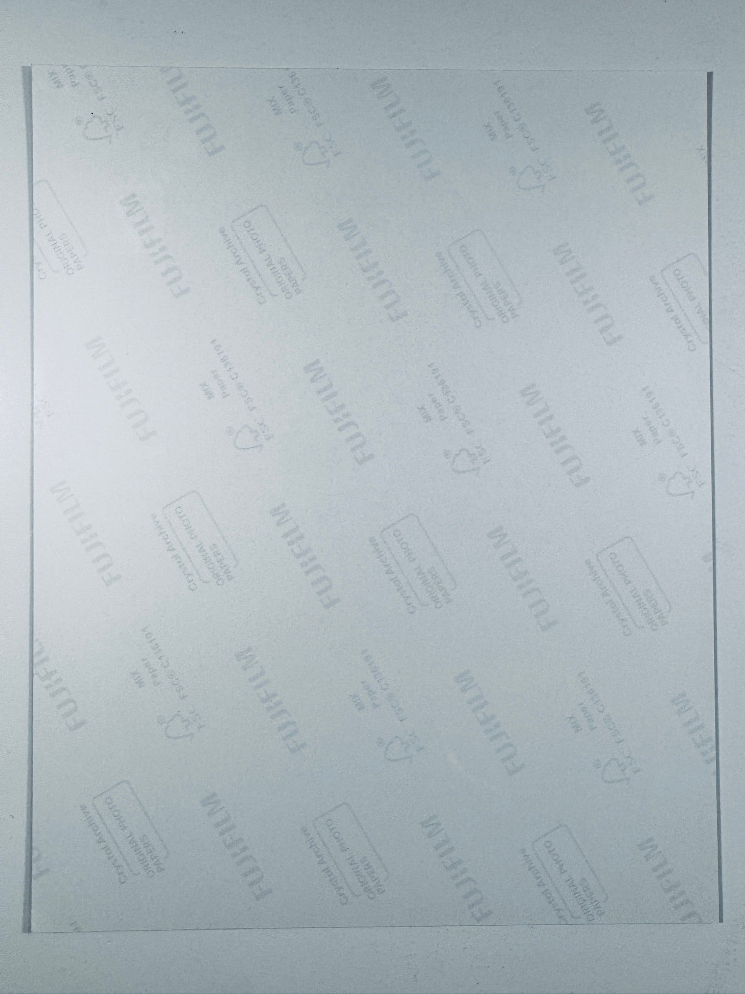 The plain white reverse side of a photographic print showing translucent Fujifilm crystal archive paper watermarks and logos.