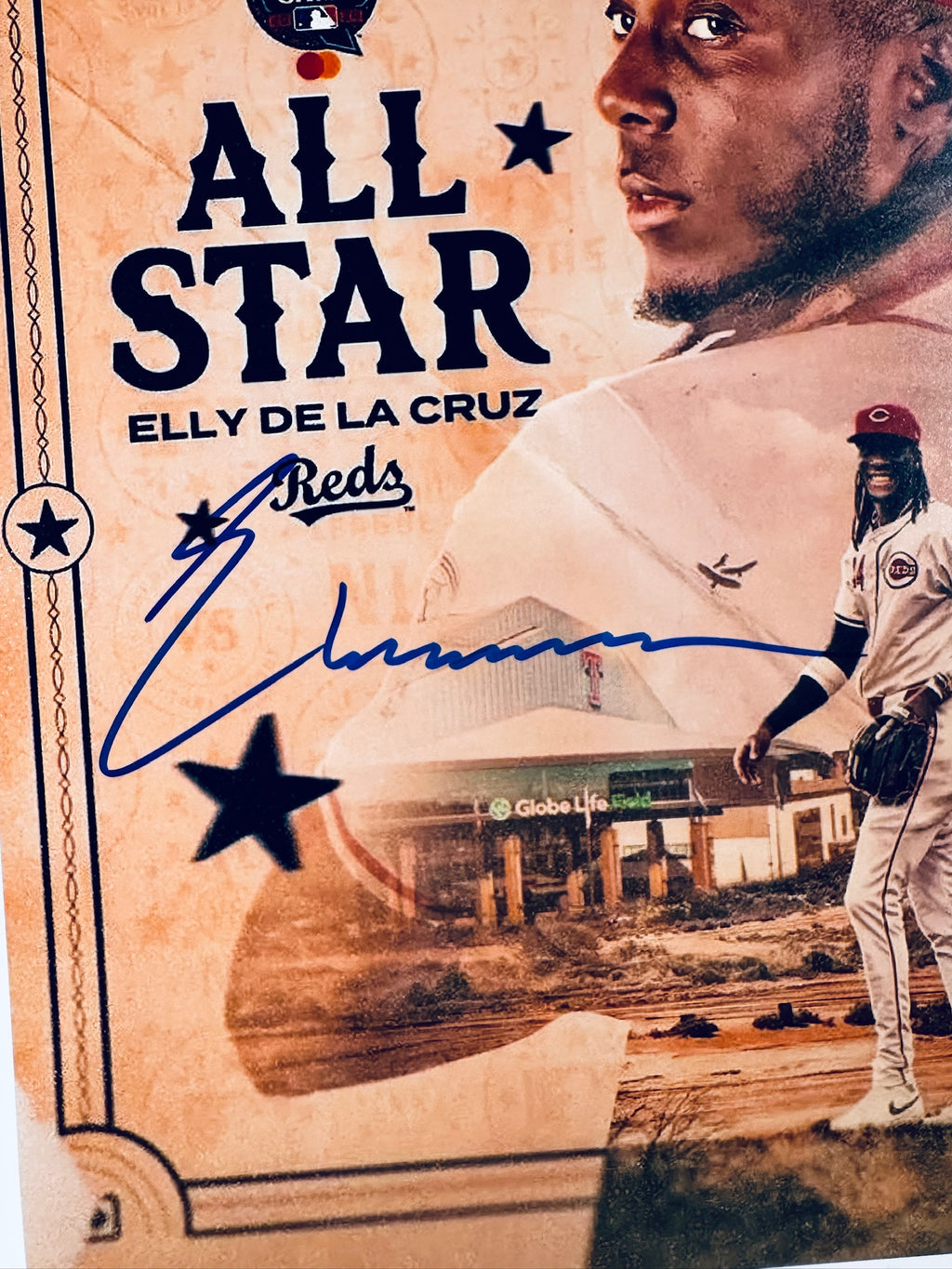 Close-up of Elly De La Cruz's signature in blue marker with the Reds inscription on the signed All-Star 8x10 photo.