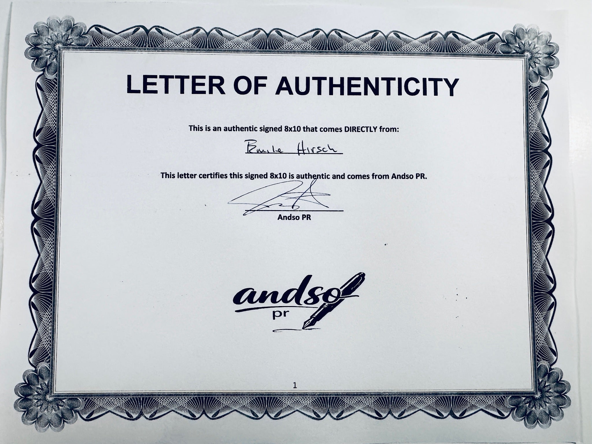 A Letter of Authenticity with a decorative blue-patterned border for an Into the Wild signed 8x10, certifying an authentic autograph coming directly from Emile Hirsch, featuring a signature at the top.