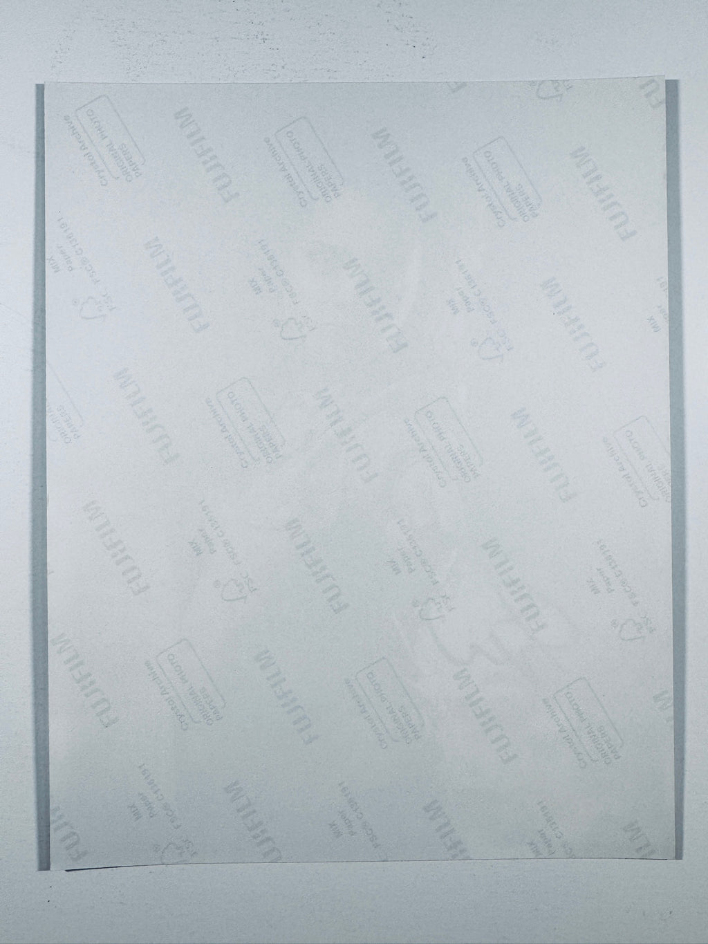 The plain white reverse side of a photographic print showing translucent Fujifilm crystal archive paper watermarks and logos.