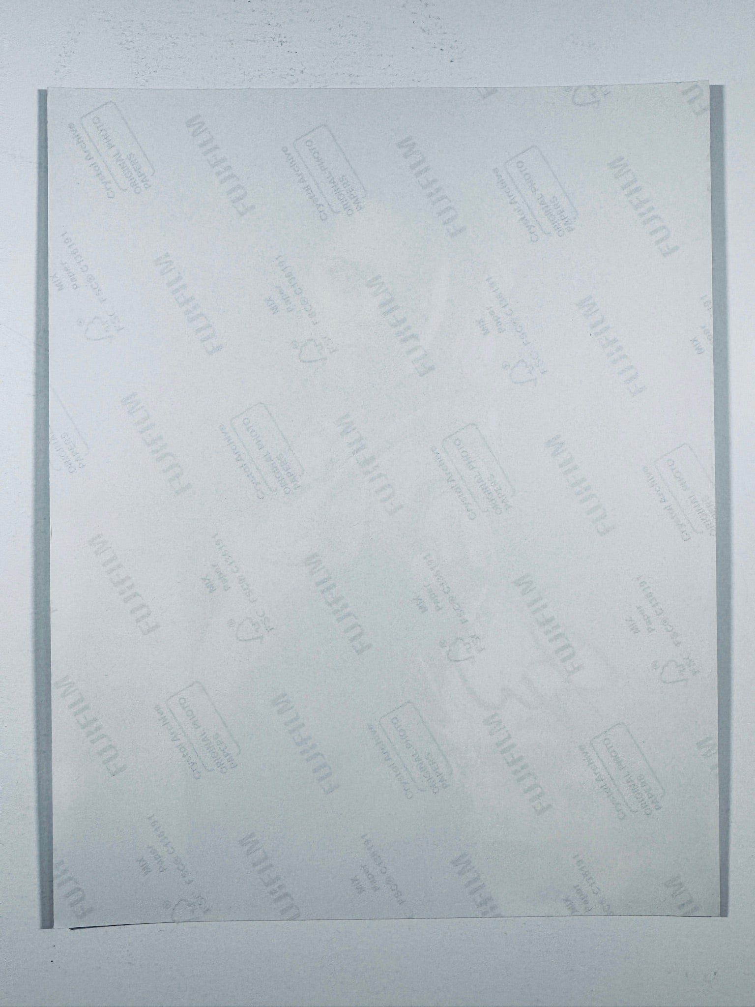 The plain white reverse side of a photographic print showing translucent Fujifilm crystal archive paper watermarks and logos.
