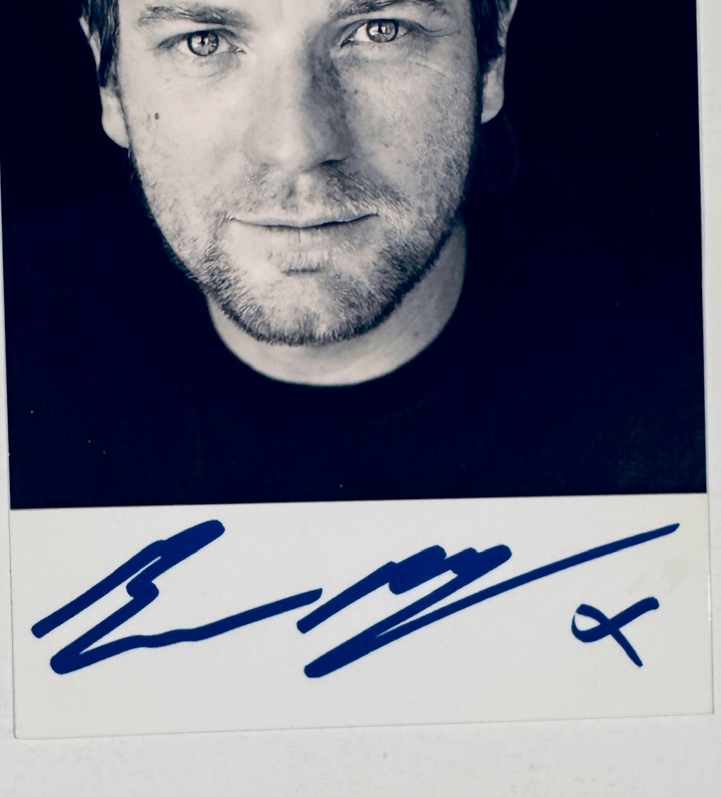 Close-up view of Ewan McGregor autograph signature in blue marker on the photo border.
