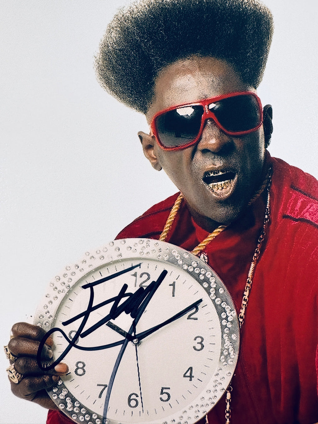 Close-up view of Flavor Flav's signature in black marker across the white face of the clock in the promotional photo.