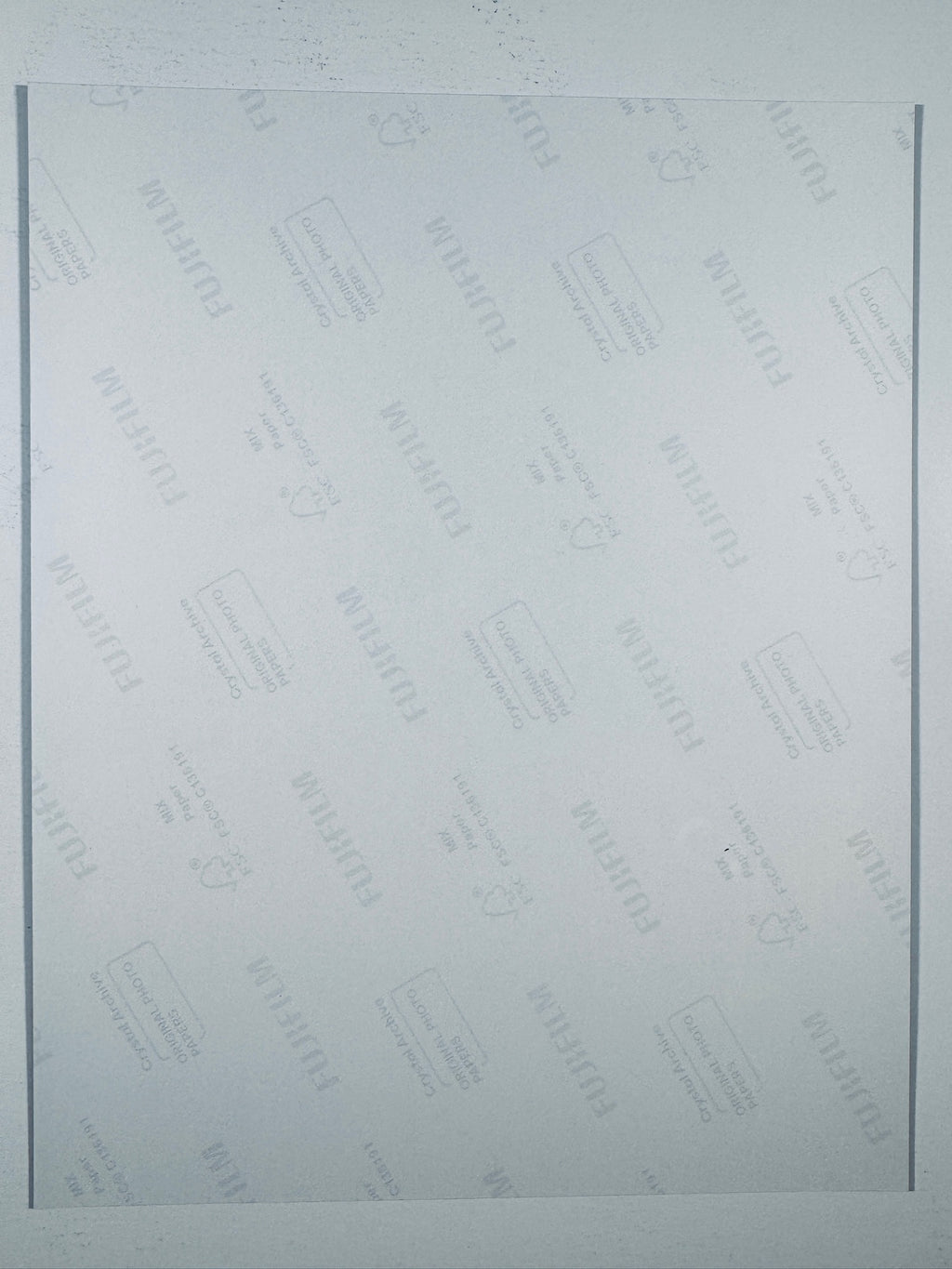 The plain white reverse side of a photographic print showing translucent Fujifilm crystal archive paper watermarks and logos.
