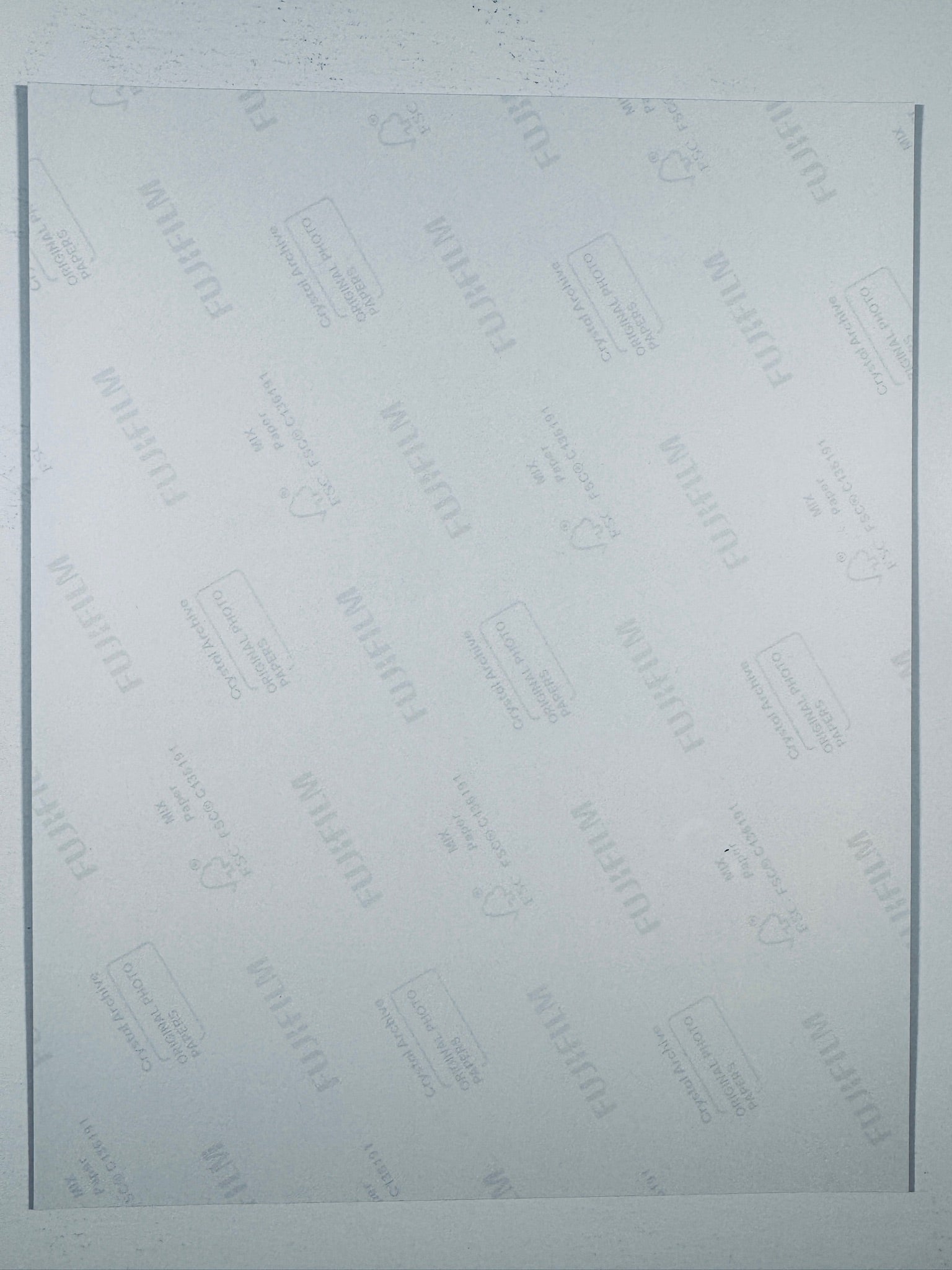 The plain white reverse side of a photographic print showing translucent Fujifilm crystal archive paper watermarks and logos.