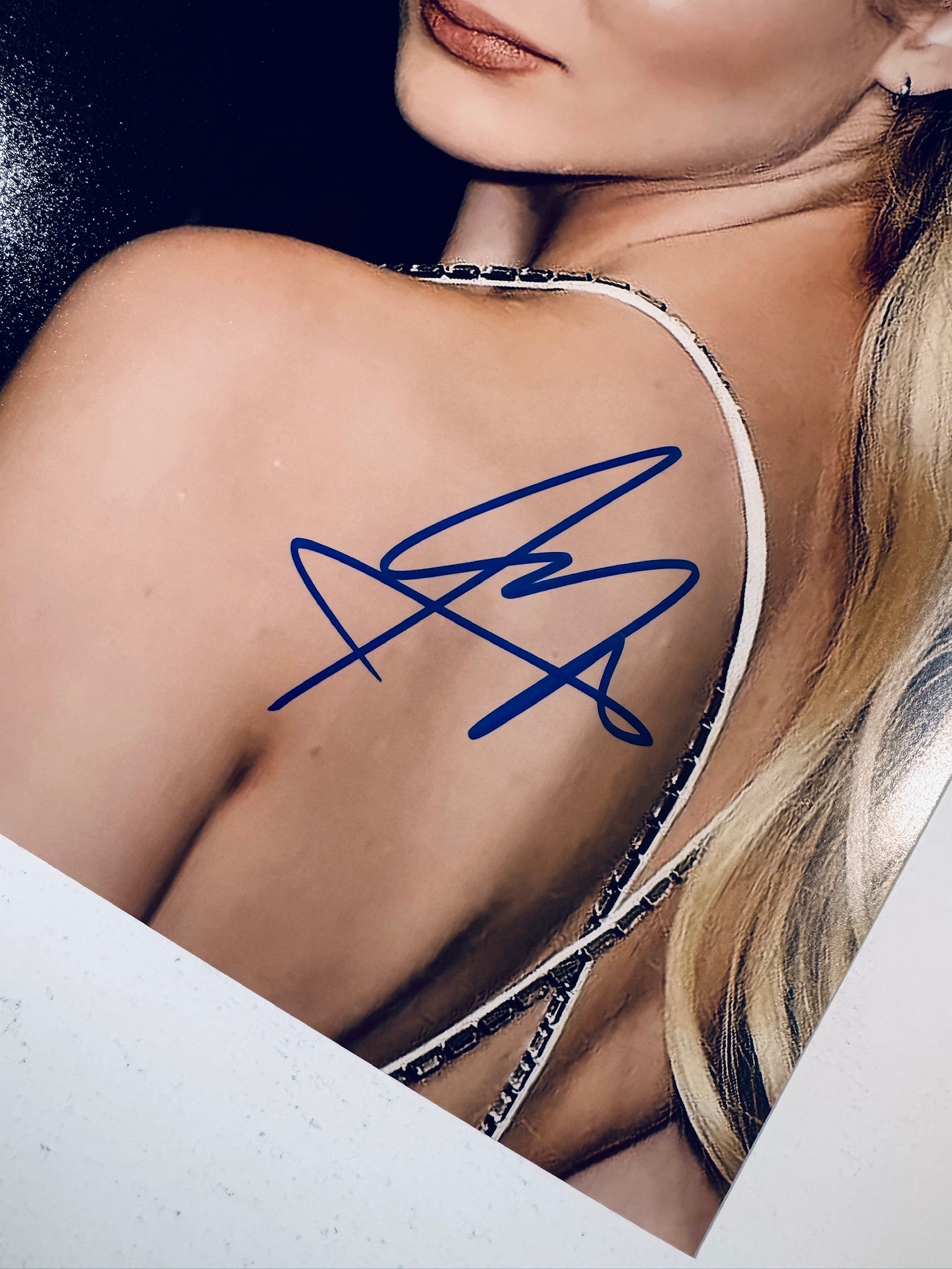 Close-up view of Freya Allan's blue signature across her shoulder and back on the promotional photograph.
