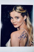 Signed full photo of Freya Allan looking over her shoulder in a white dress, featuring a blue autograph.