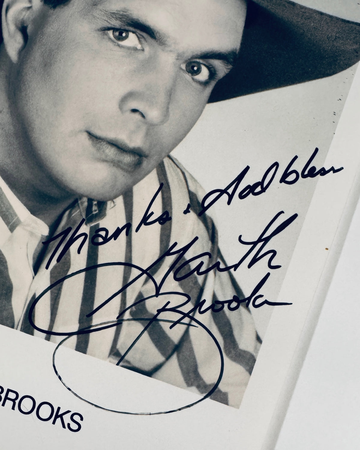 A close-up of a signed black-and-white portrait print of actor GARTH BROOKS, featuring his signature in dark ink across the face and a hat in the upper right corner.