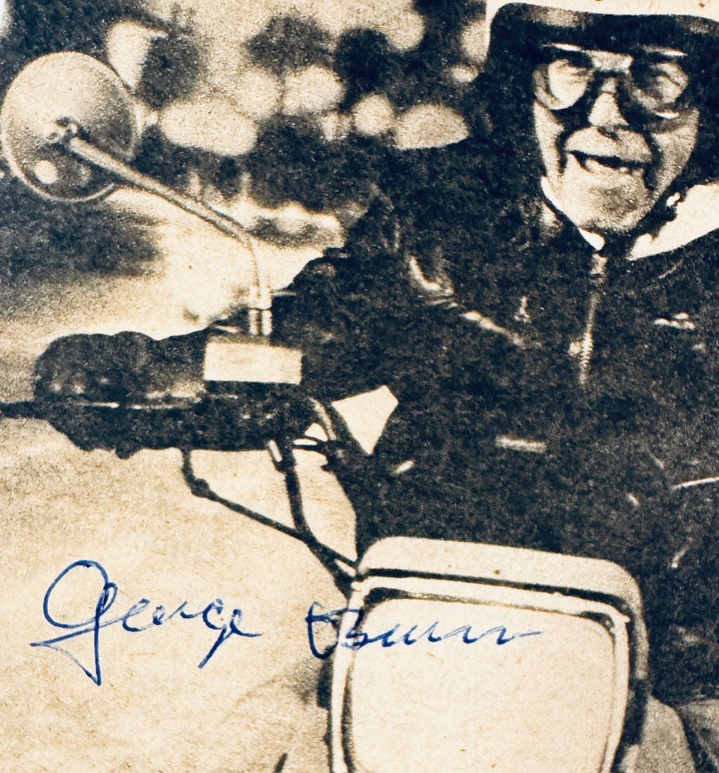 Close up detail of authentic George Burns signature in blue ink on motorcycle photo.