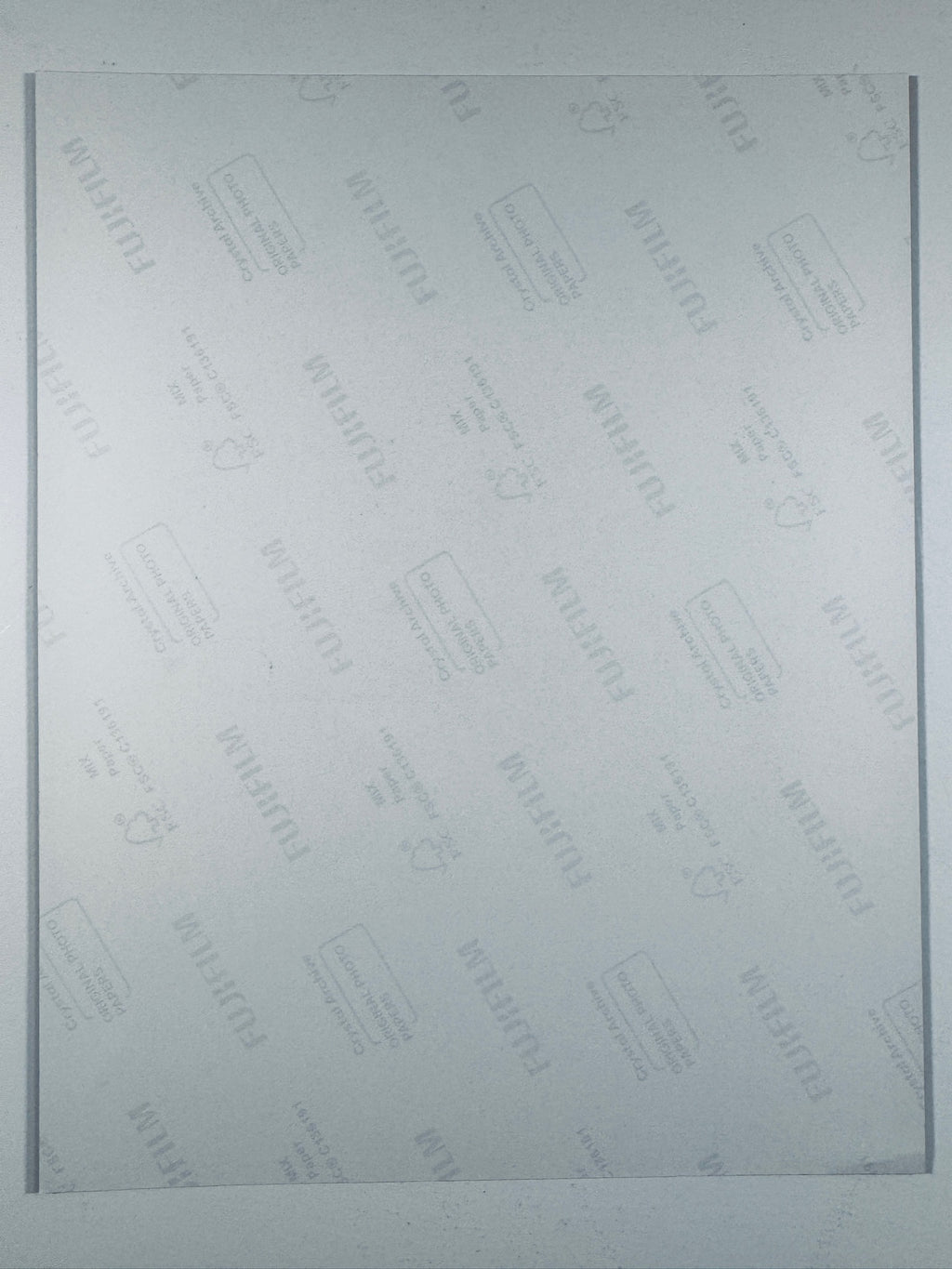 The plain white reverse side of a photographic print showing translucent Fujifilm crystal archive paper watermarks and logos.