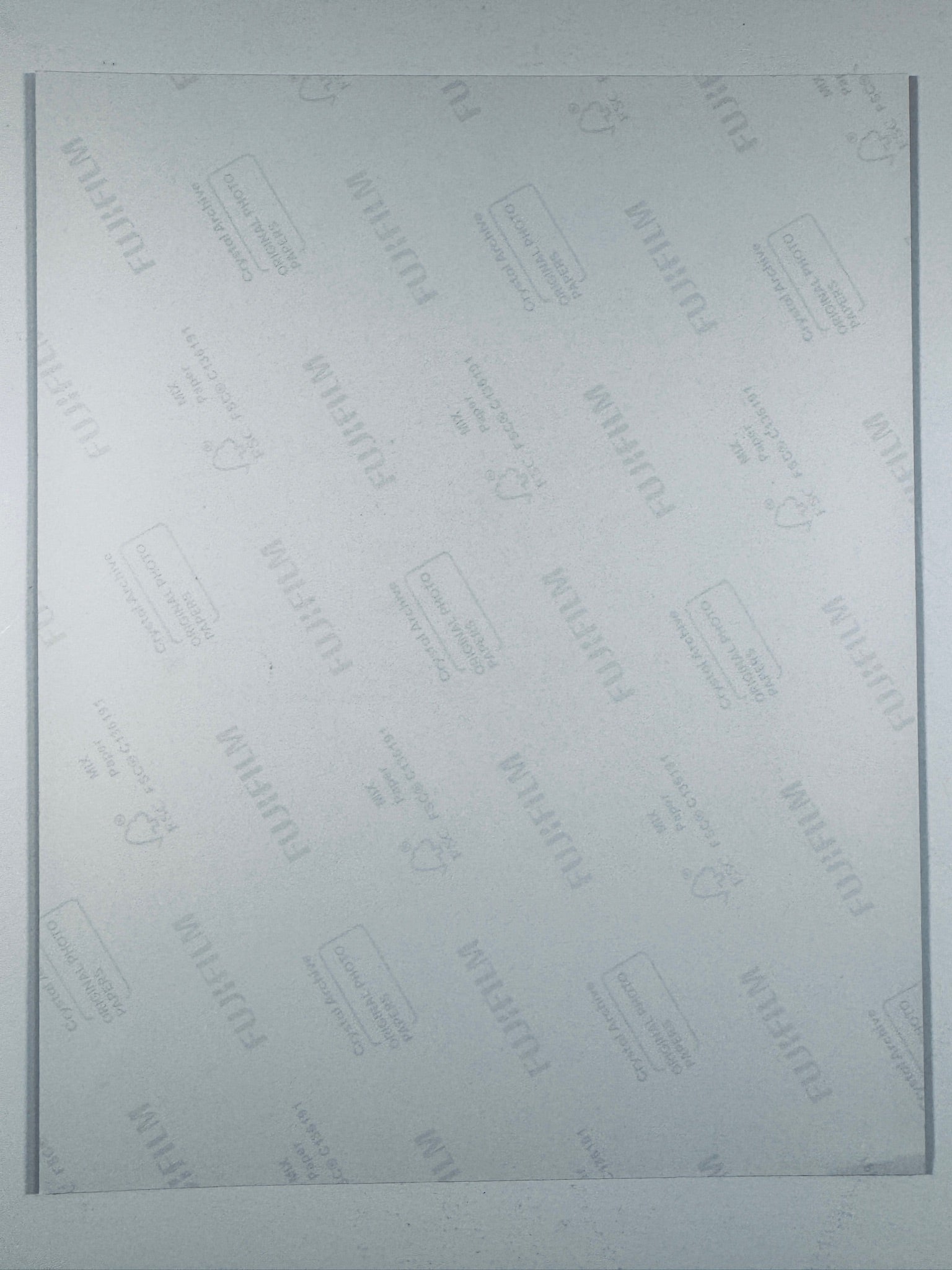 The plain white reverse side of a photographic print showing translucent Fujifilm crystal archive paper watermarks and logos.