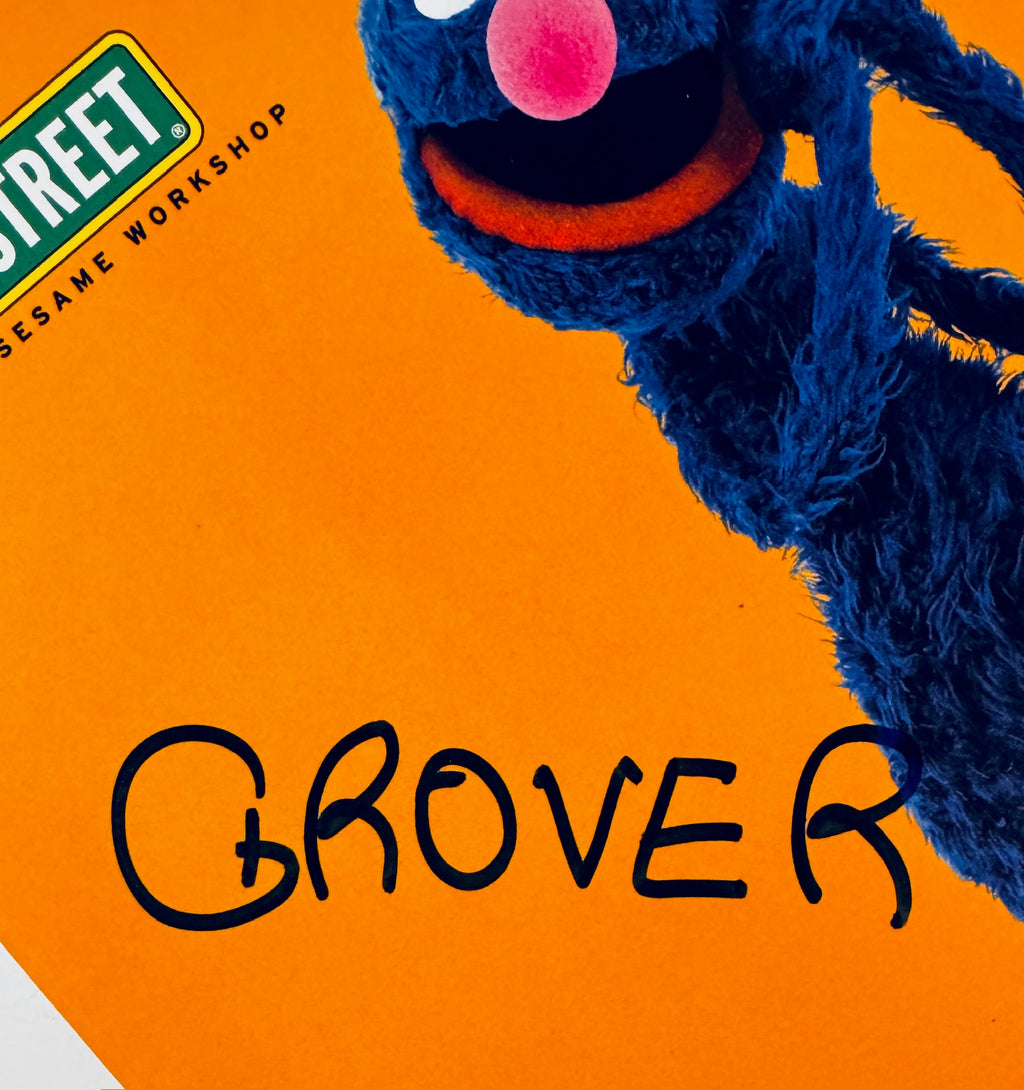Close-up view of the Grover autograph in black marker next to the Sesame Street logo.