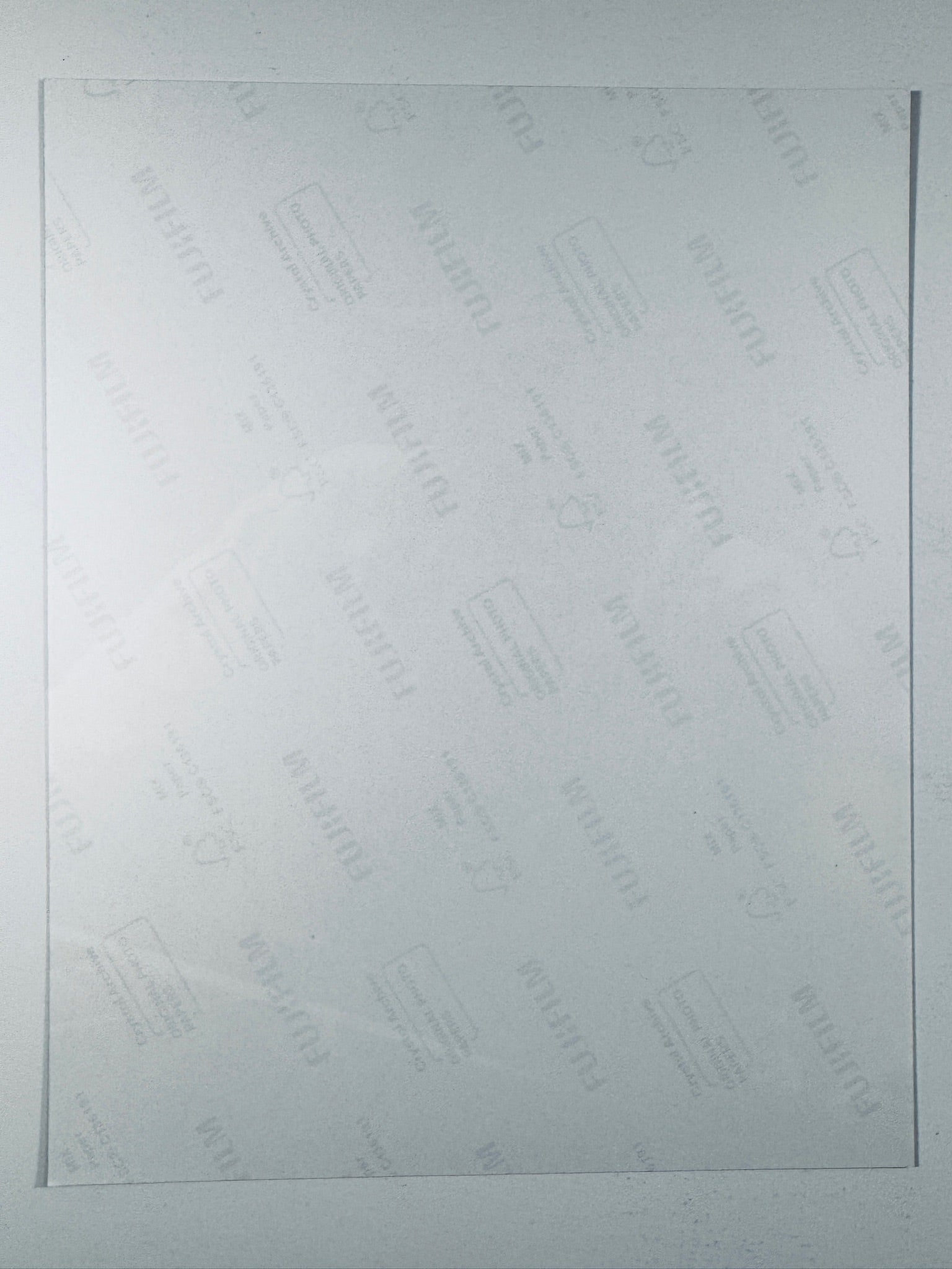 The plain white reverse side of a photographic print showing faint translucent watermark patterns and repeating Fujifilm paper logos.