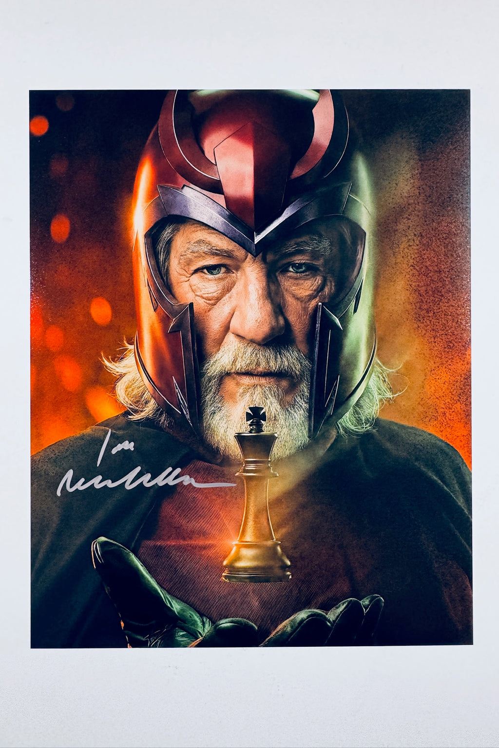 An autographed photo print of Ian Malcolm as Magneto from Marvel, signed in white ink across the lower left. The print features a white border and is shown against a neutral light gray background.
