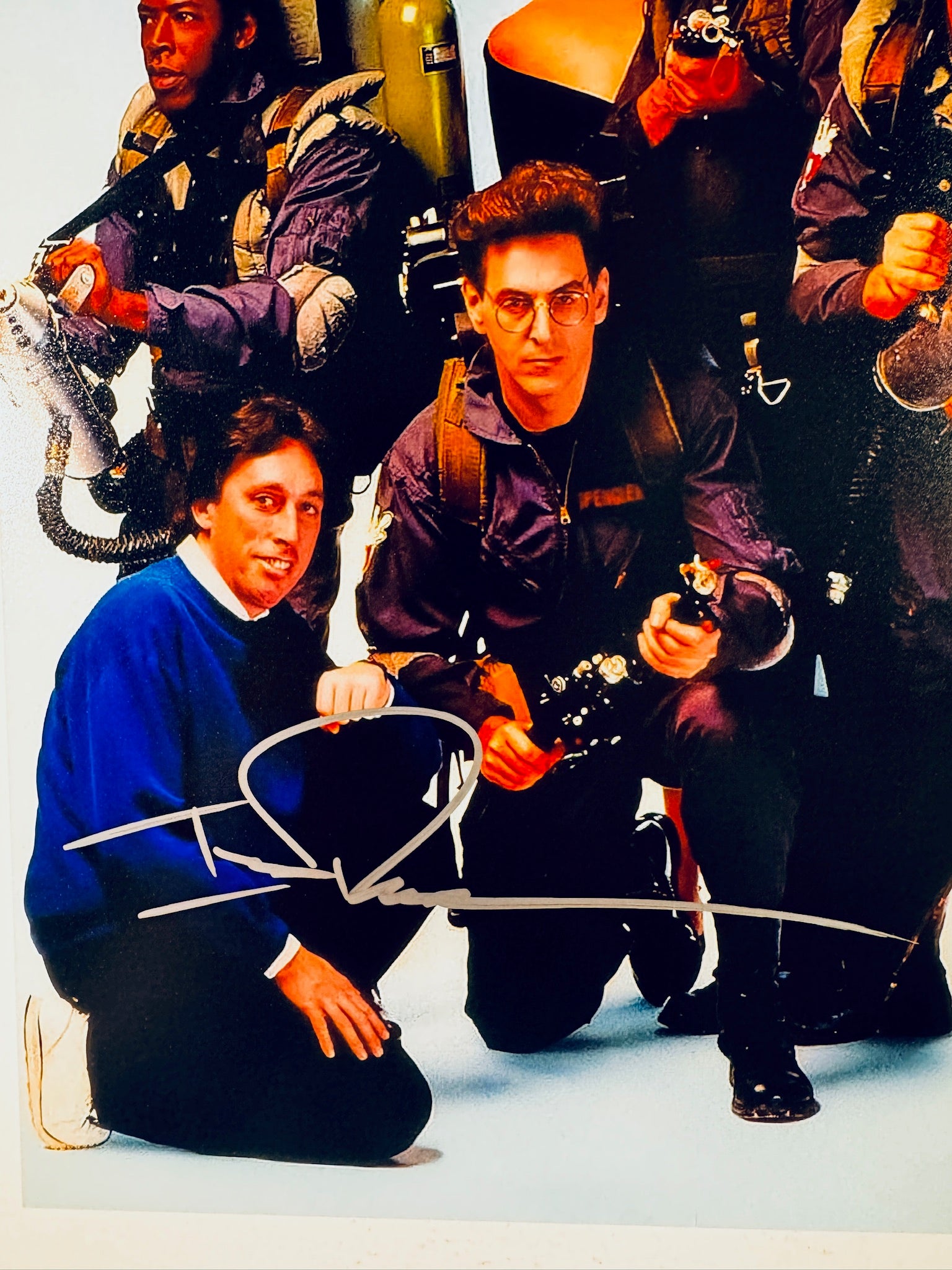 Close-up view of Ivan Reitman's signature in silver marker on the Ghostbusters promotional matte photo.