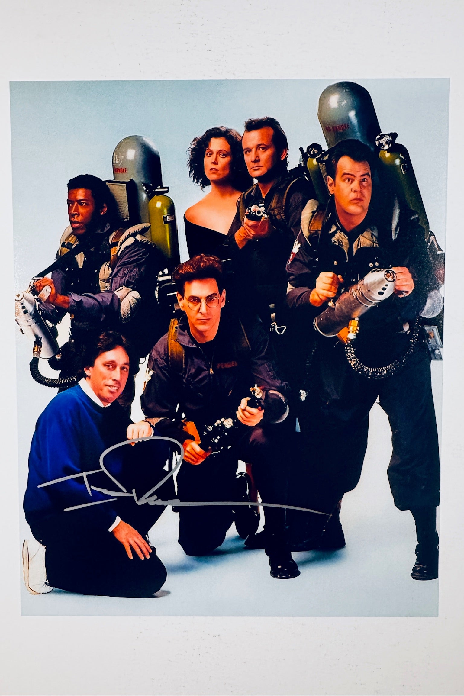 Cast photo from Ghostbusters featuring the main characters alongside director Ivan Reitman, with a bold silver ink autograph by Ivan Reitman.