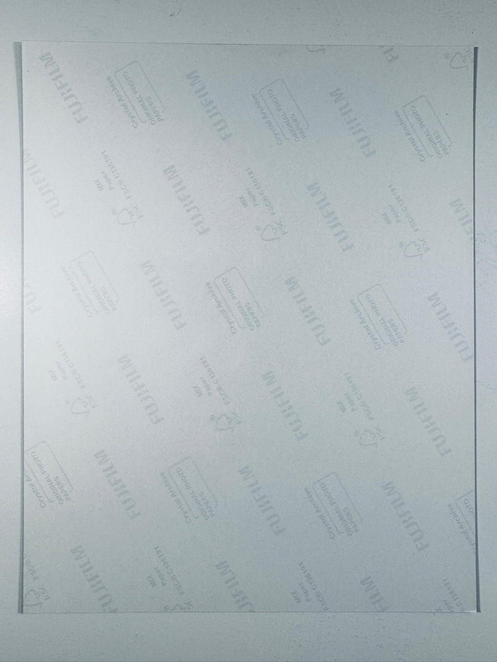 The plain white reverse side of a photographic print showing translucent Fujifilm crystal archive paper watermarks and logos.