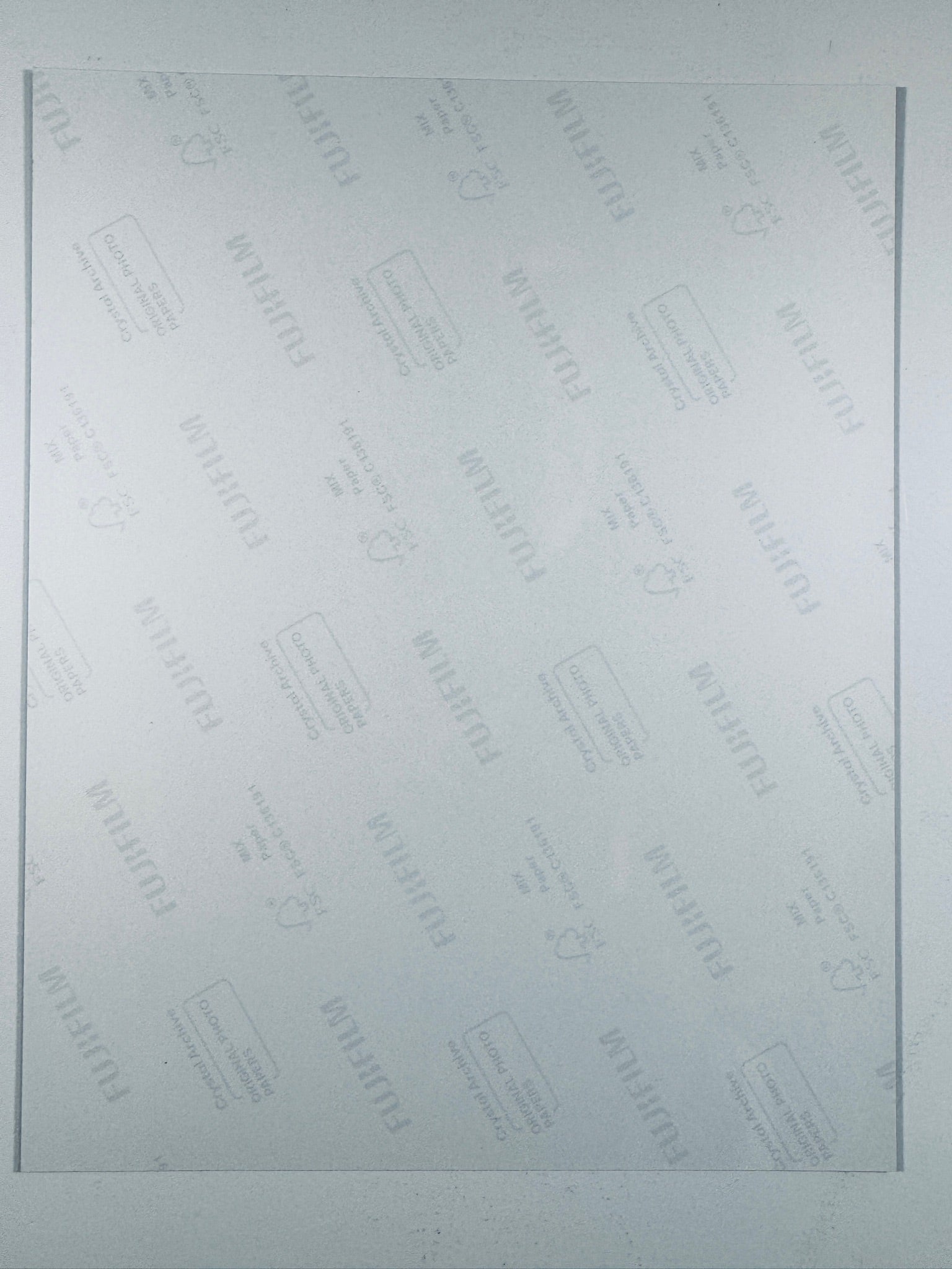 The plain white reverse side of a photographic print showing translucent Fujifilm crystal archive paper watermarks and logos.