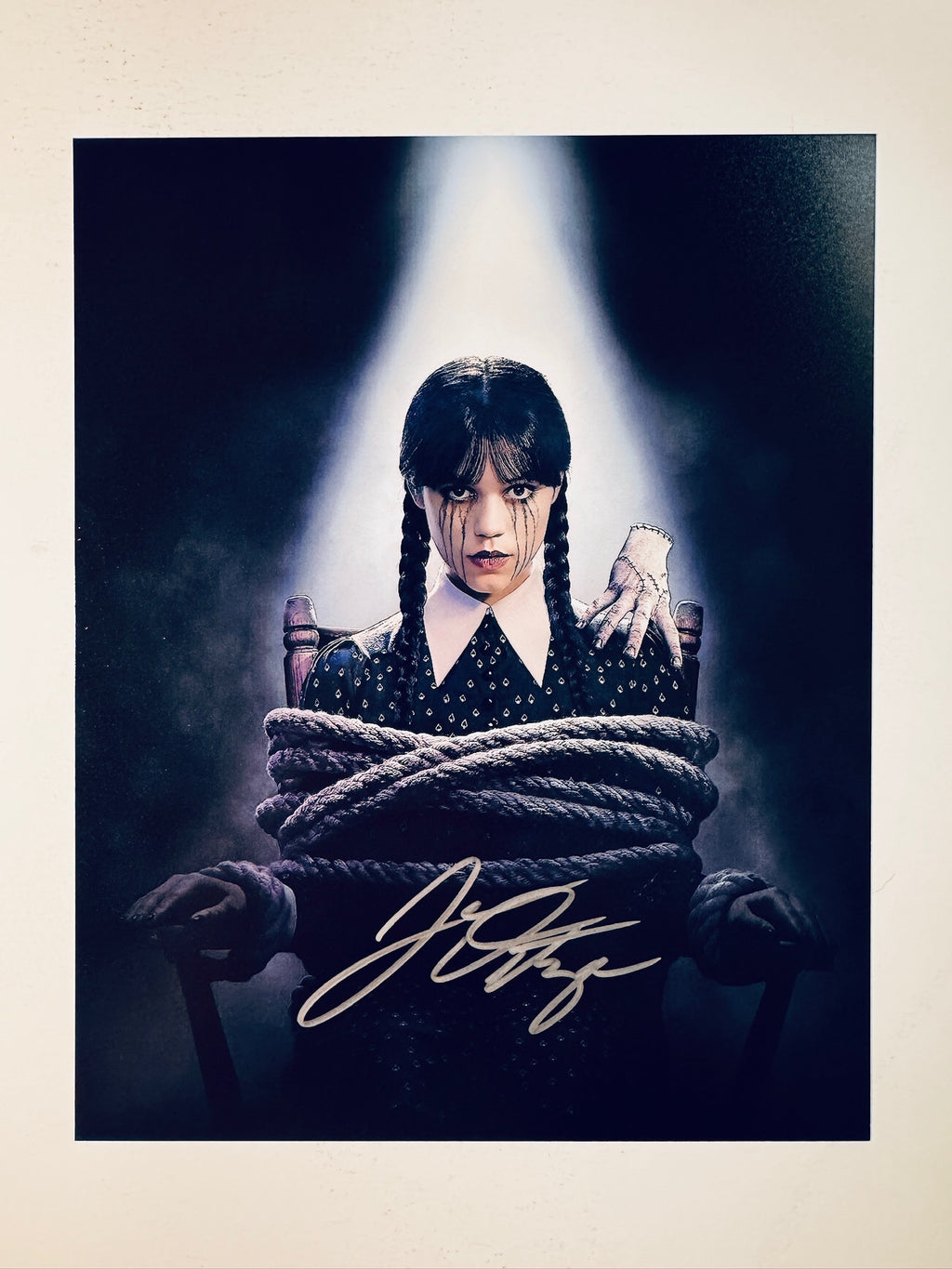 Jenna Ortega hand-signed 8x10 matte photo featuring Wednesday Addams tied up in a chair with Thing from the Netflix series Wednesday.