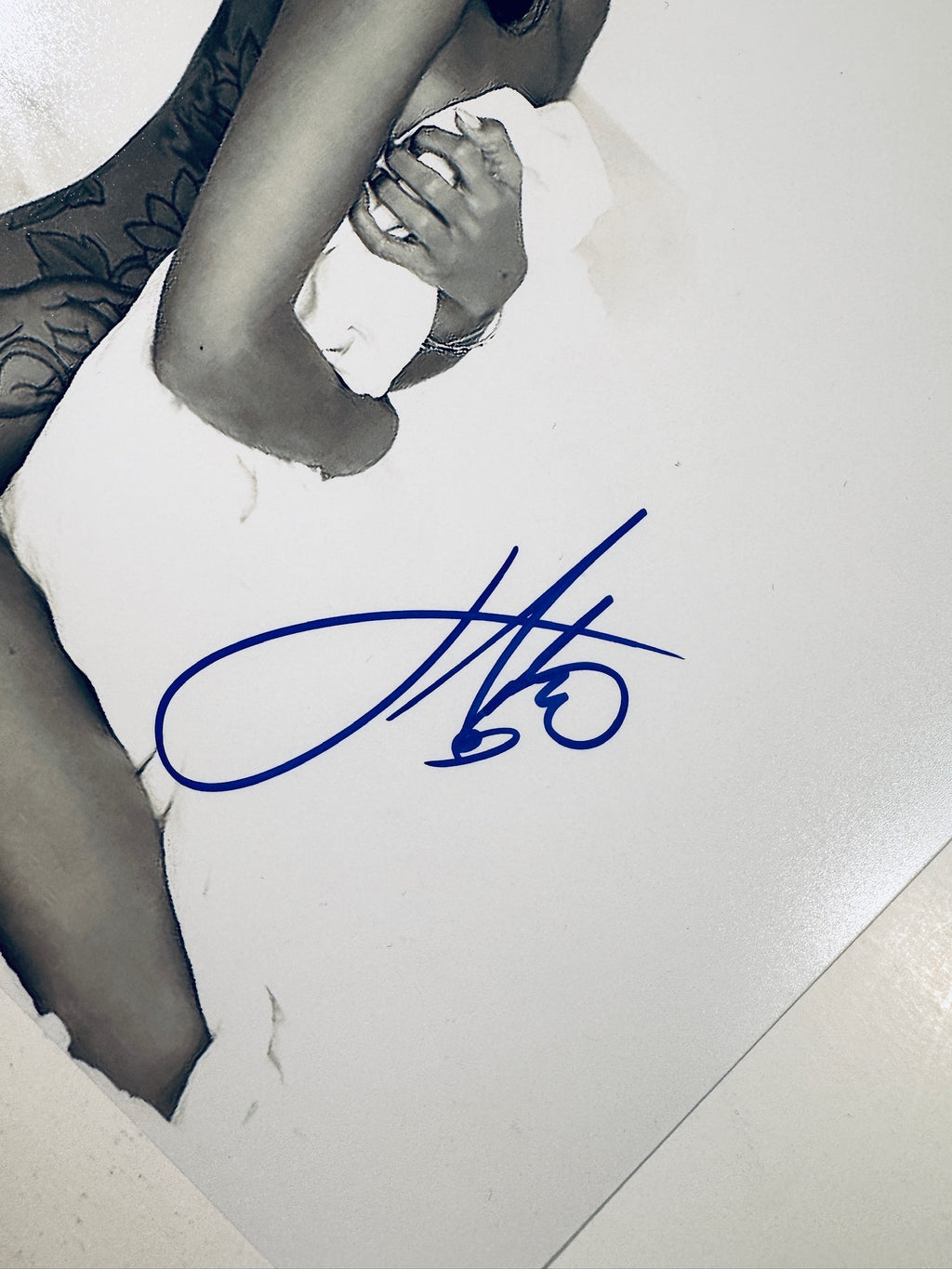 Close-up view of Jhene Aiko's blue signature across the white sheet and bed on the promotional photograph.